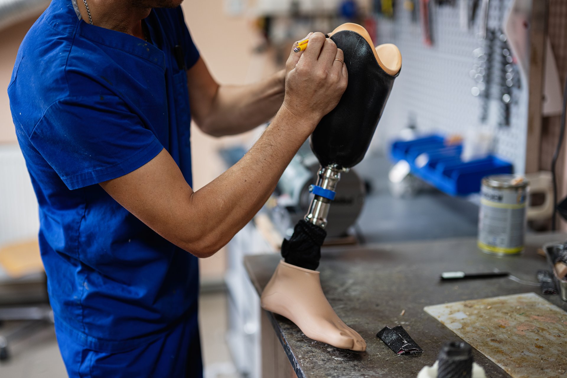 A skilled technician works meticulously on a prosthetic leg in a workshop environment, showcasing attention to detail and dedication to aiding mobility and rehabilitation.