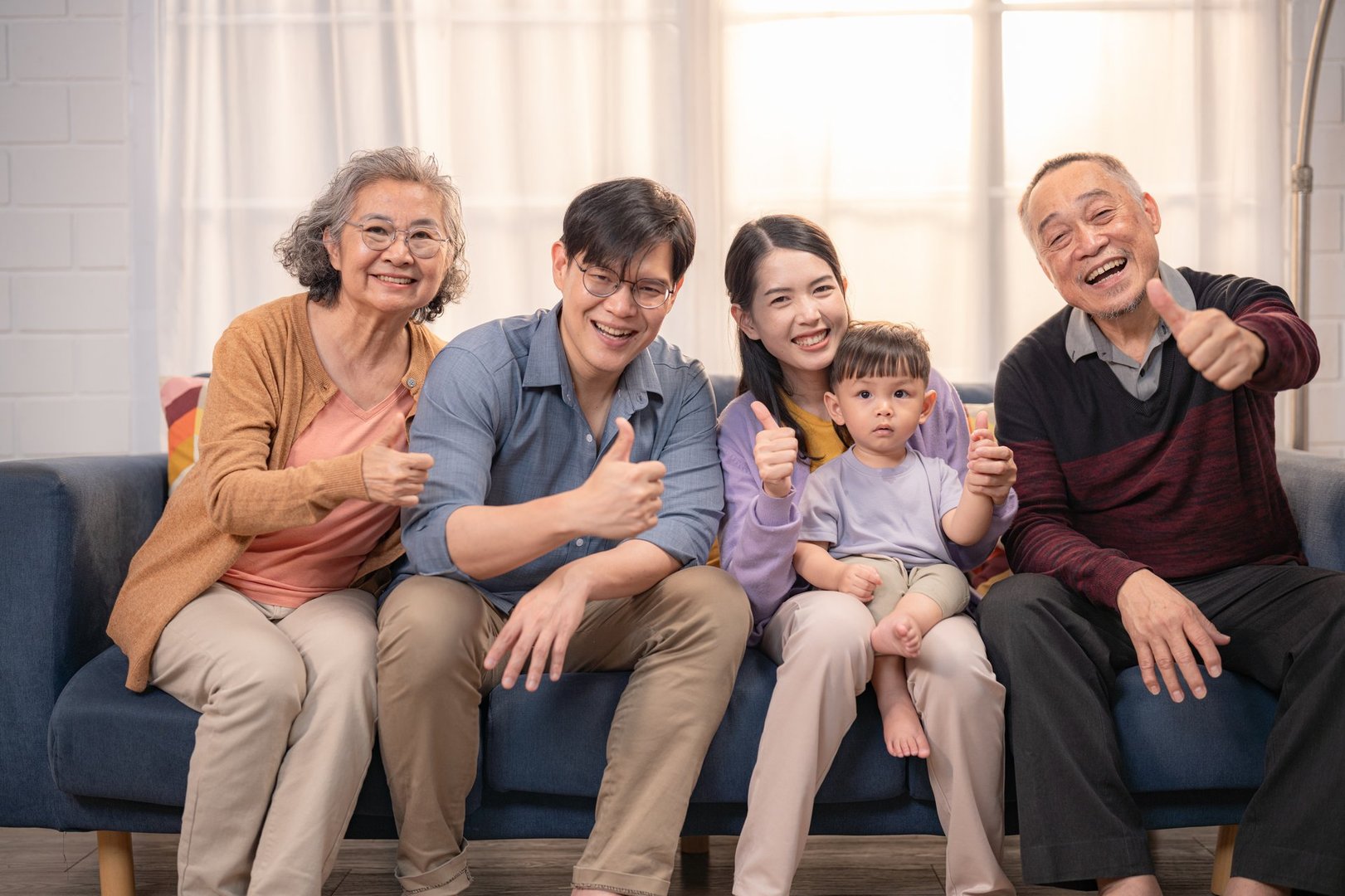 A family of five enjoys quality time together in a cozy living room. They smile and give thumbs up, showcasing a moment of joy and togetherness during a casual gathering.