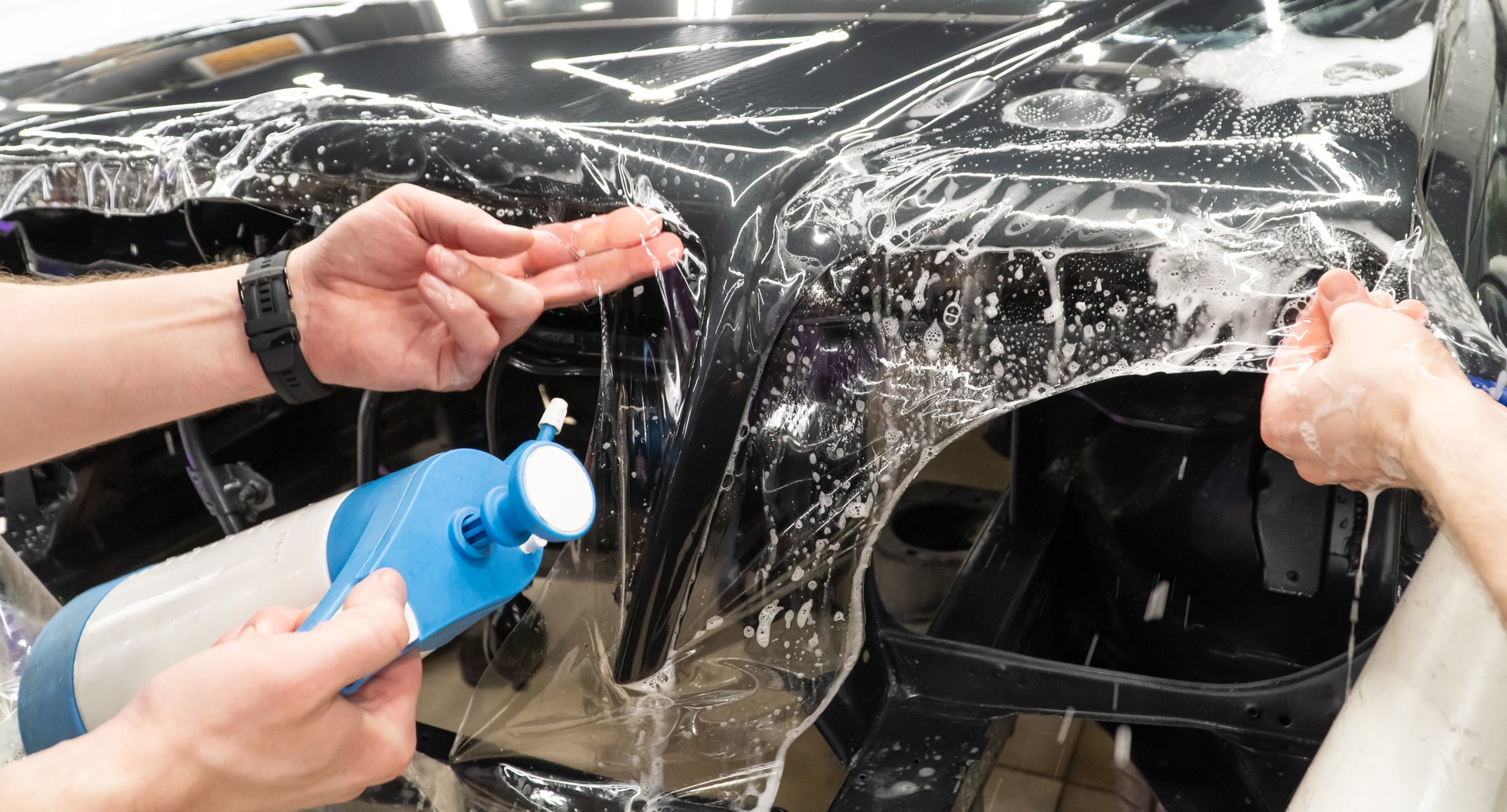 A car wrapping specialist applies a polyurethane film to the car. Selective focus. Armored film on the side car. Car wrapping close-up.
