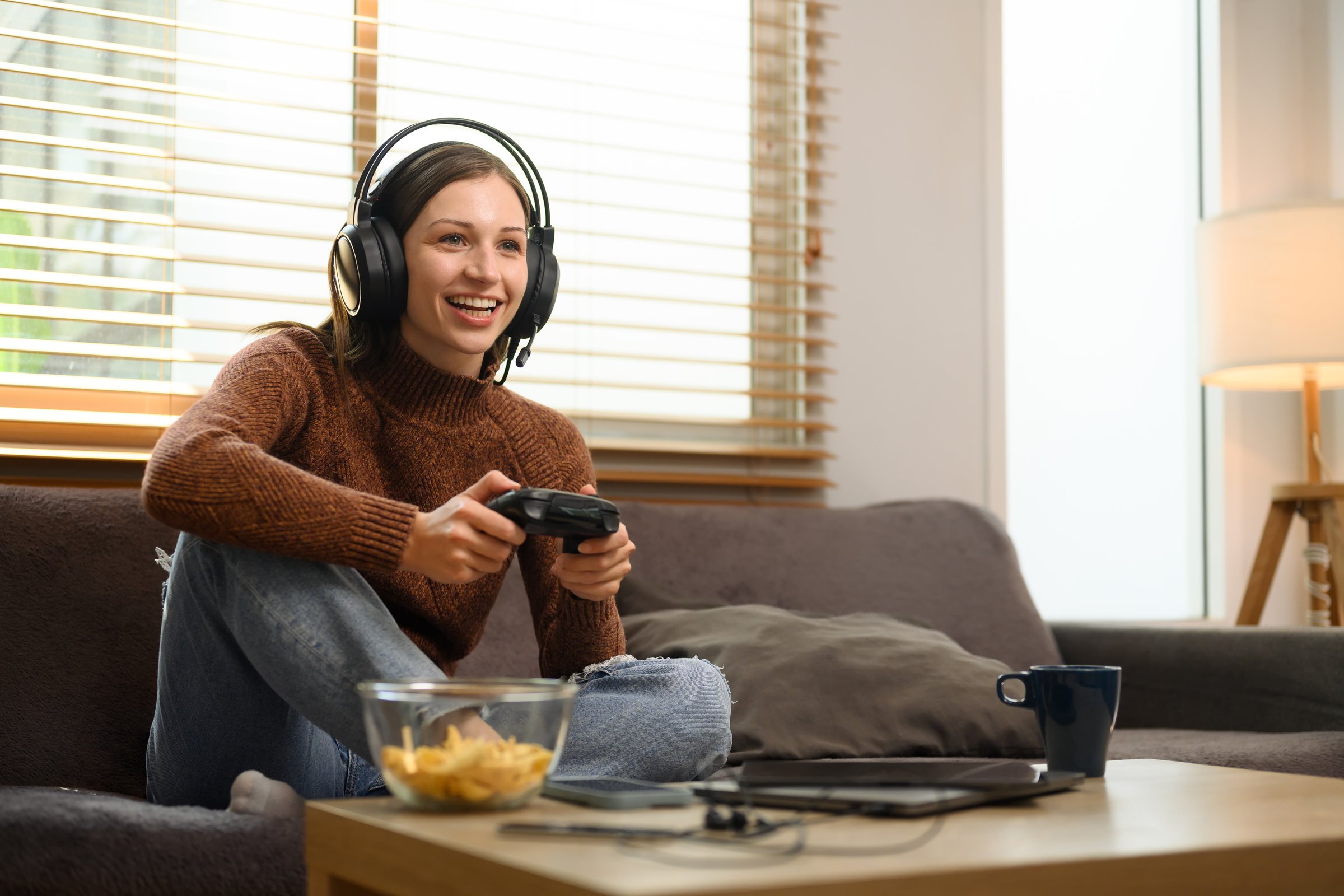 Overjoyed young woman wearing headset playing video game with joystick in at home.