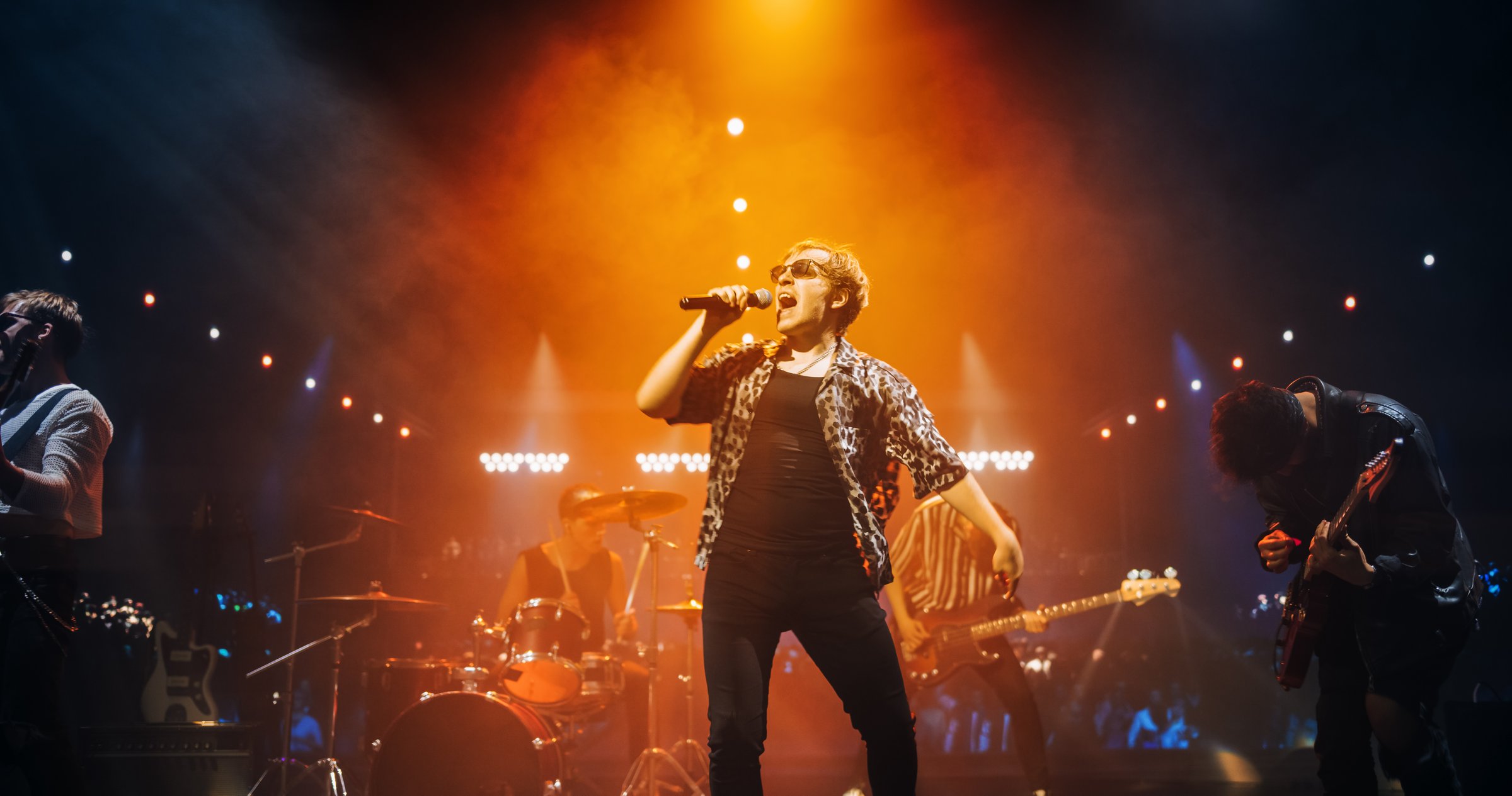 Rock Band Delivers a Captivating Concert with Lead Singer Passionately Performing on Stage with Falling Confetti, Surrounded by Band Members, Creating an Intense and Immersive Musical Atmosphere