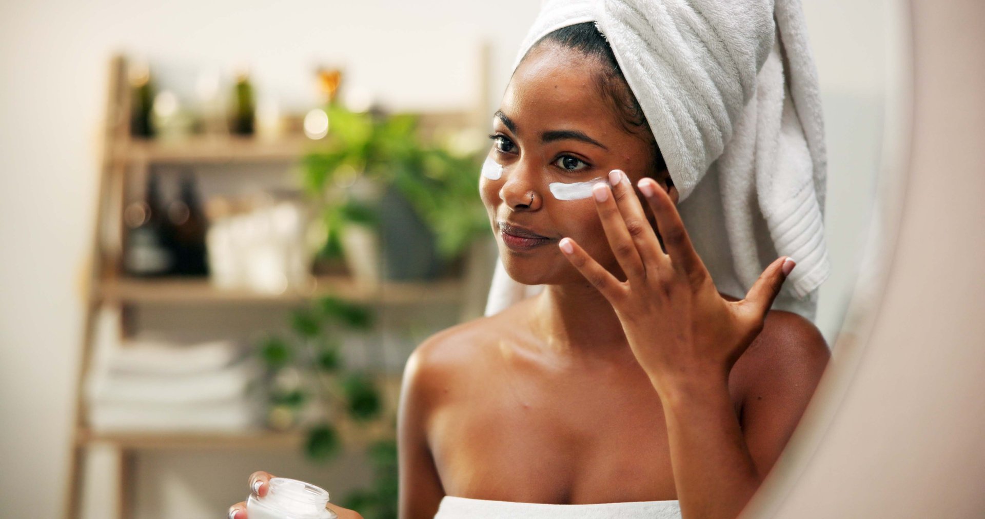 Mirror, cream and woman with beauty, skincare and home with cosmetics, glow and wellness. Container, person and girl in bathroom, healthy skin, morning or reflection with lotion, shine or dermatology