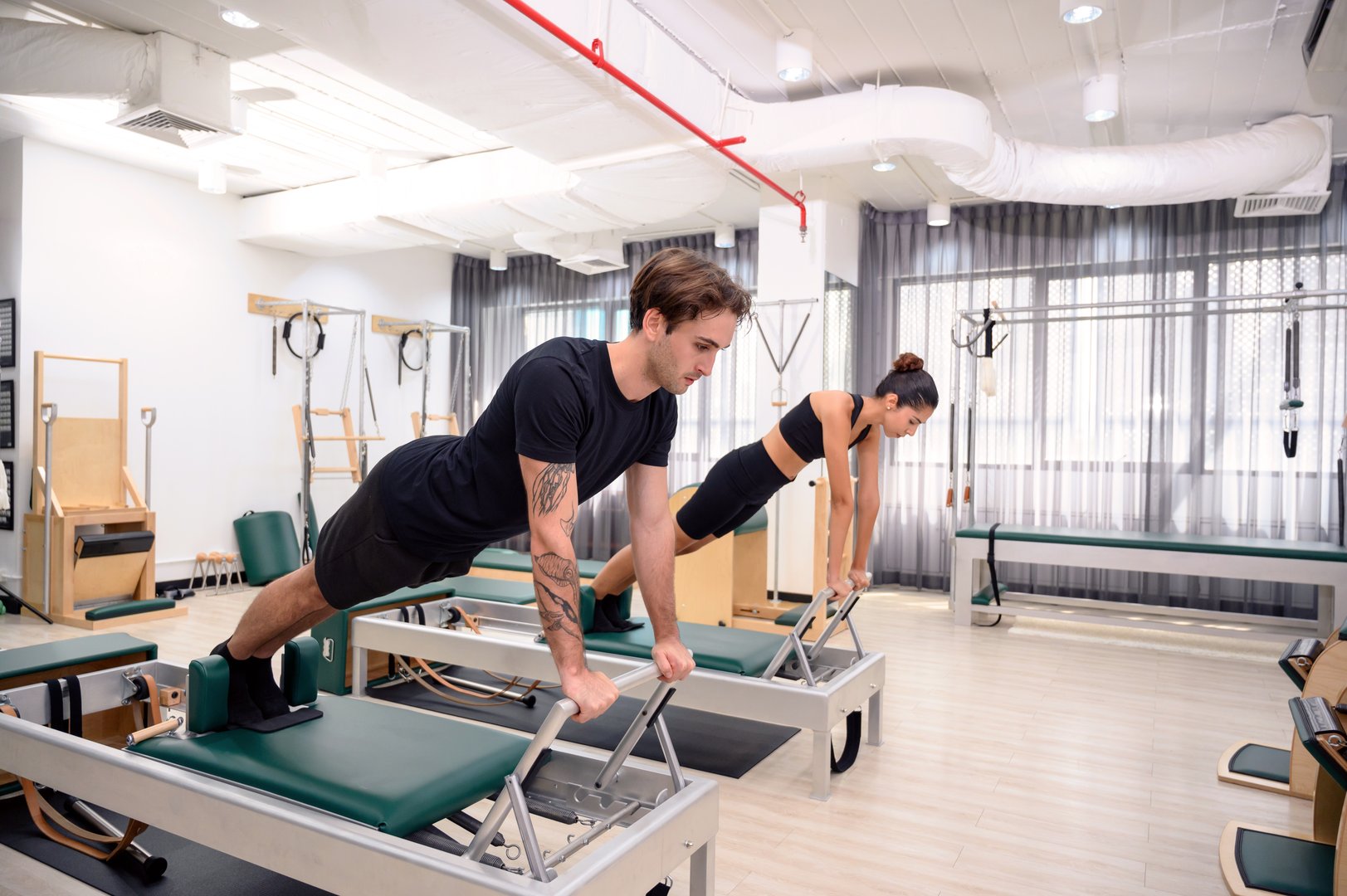 Couple enjoying pilates classes in fitness studio. Men and women strengthen muscles to maintain physical health