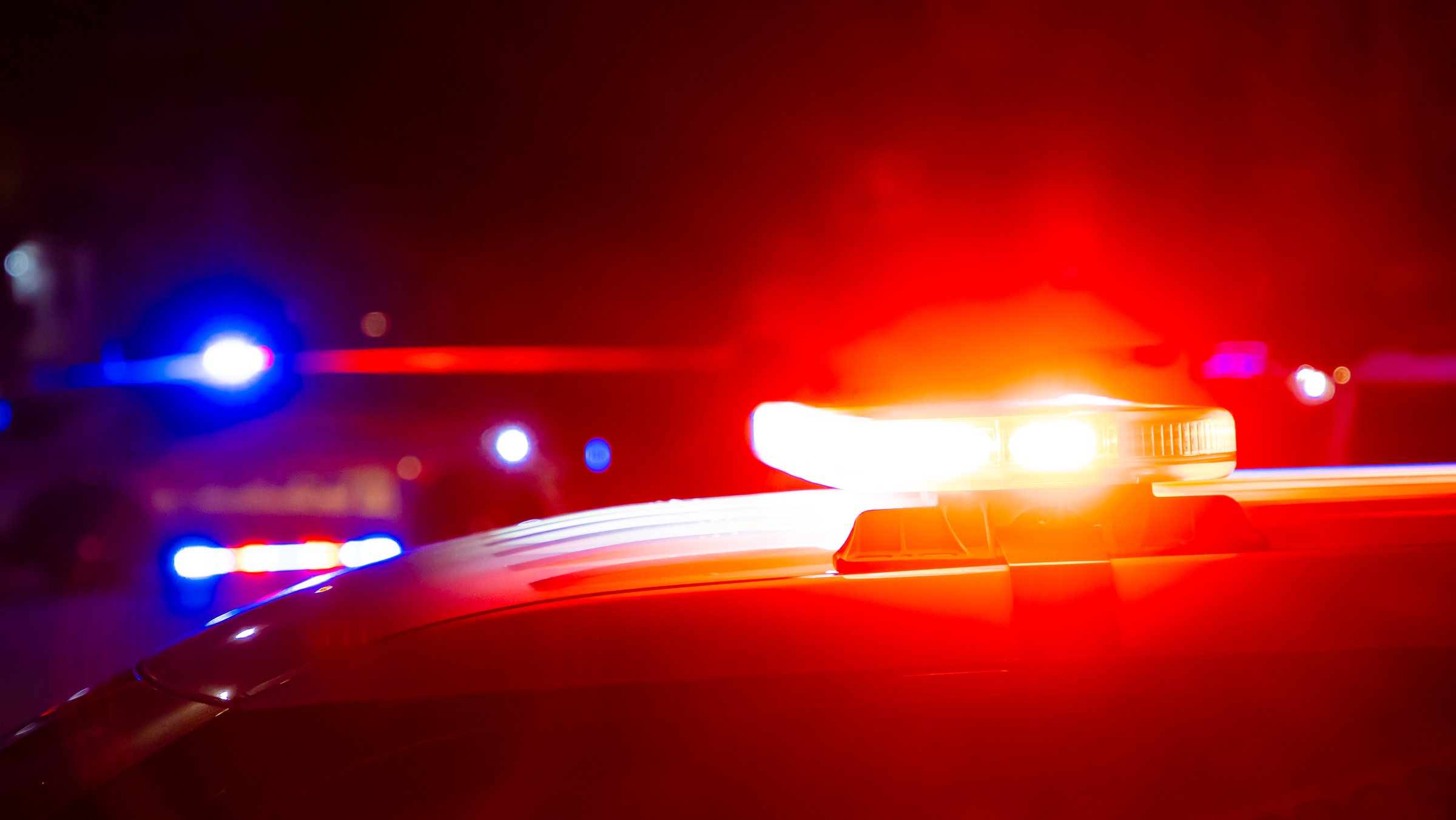 Red and blue police lights on a car at a crime scene at night