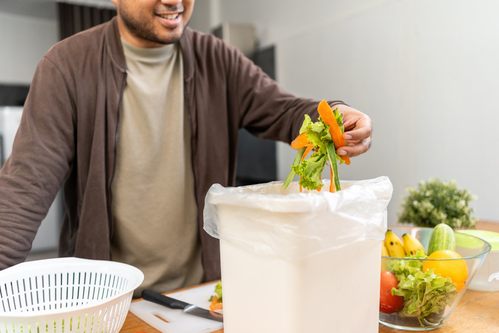 Ecology compost supply Kitchen waste recycling composter environmentally friendly. The young man throws leftover fruit peel egg shell and vegetables reduce waste