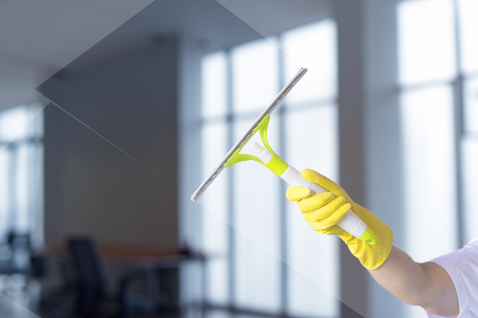 Cleaning windows in a light room. Cleaning glass with a scraper on a blurred background.