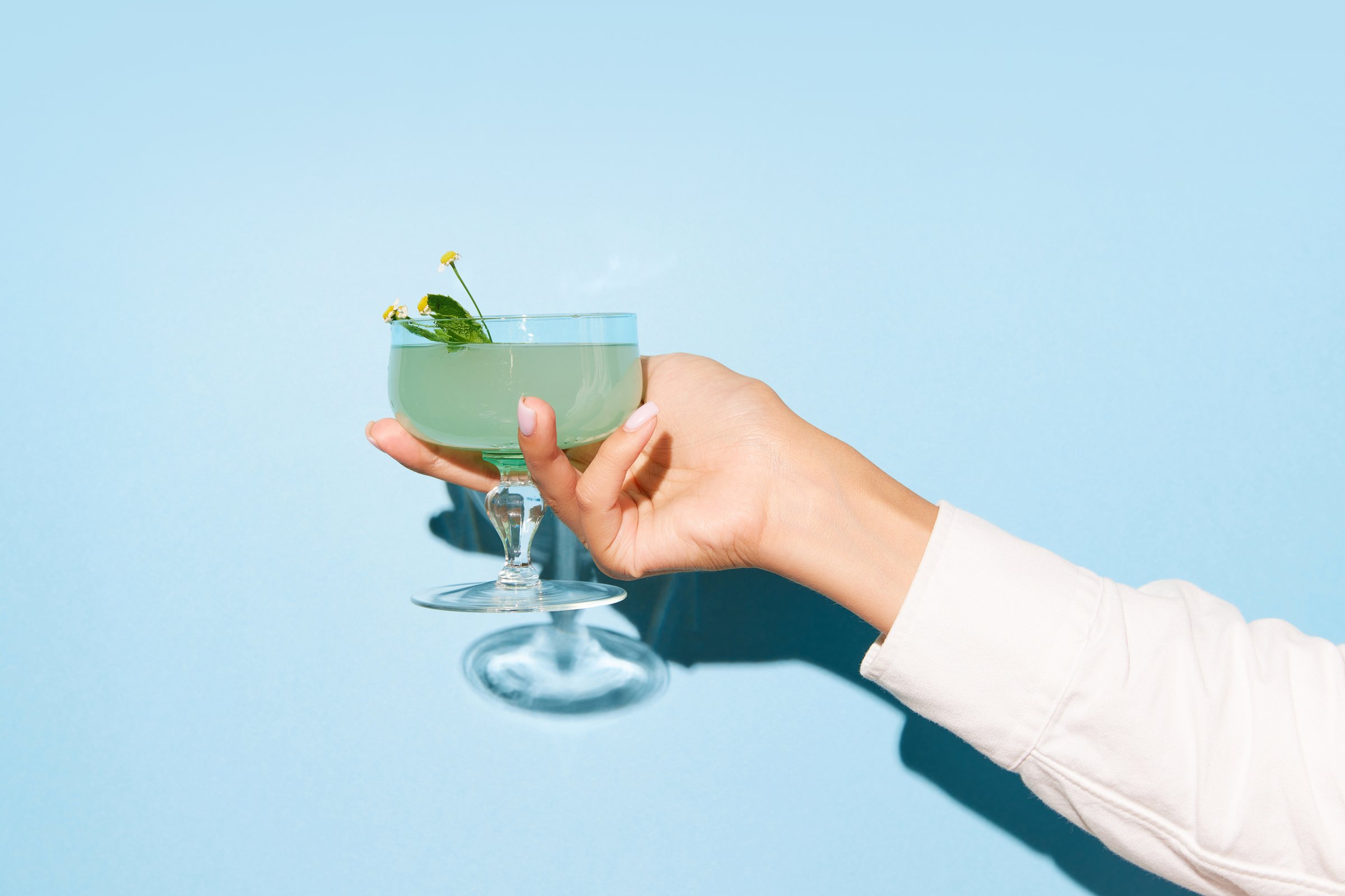Women hand holding glass with margarita cocktail on light blue pop art background. Copy space for ad. Concept of party, relax, alcohol.