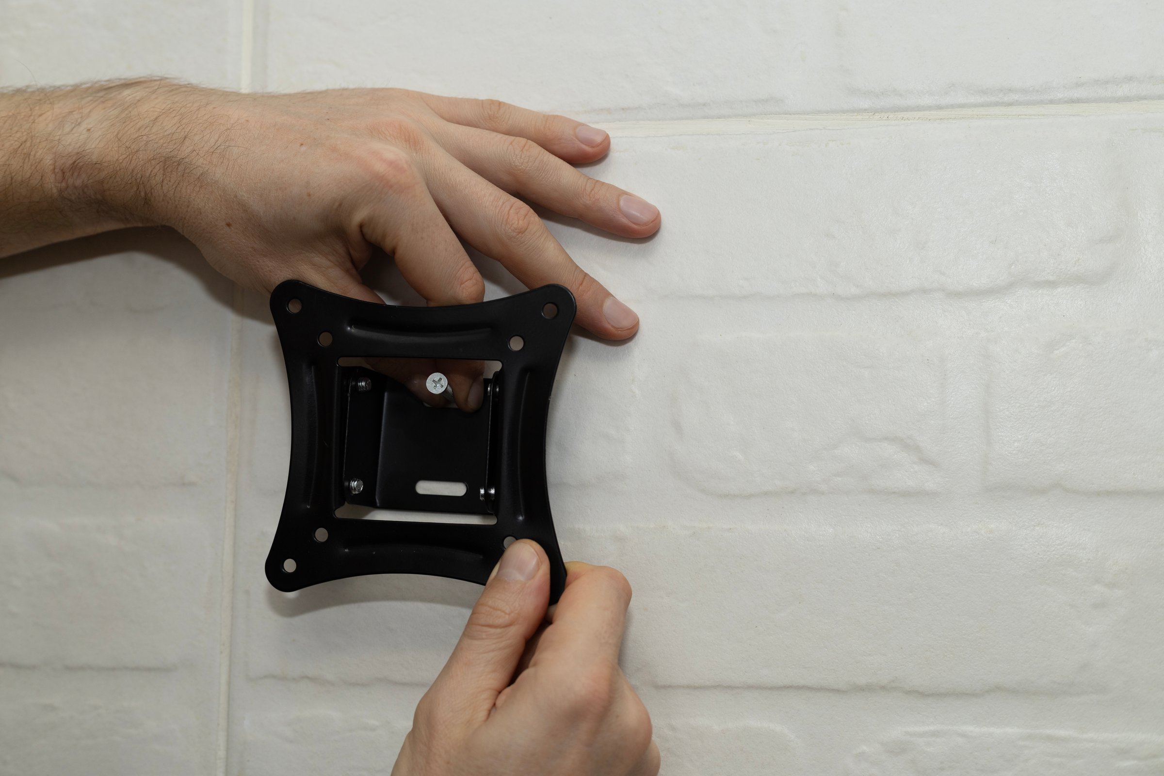 A man tries on a white wall mount bracket, close up