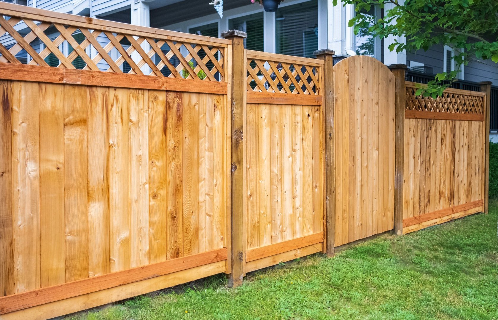 Nice wooden fence around house with green lawn showcasing quality fencing work