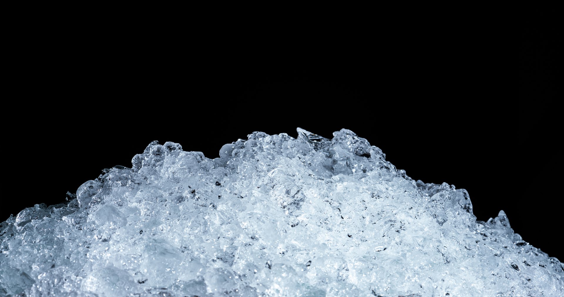 Pile of crushed ice cubes on dark background with copy space. Crushed ice cubes foreground for beverages.