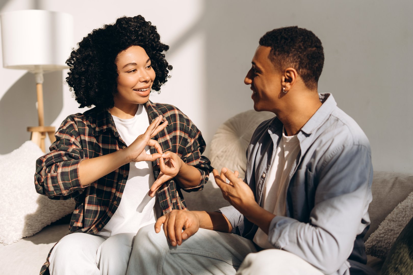 Young African American woman using sign language while talking with a man at home