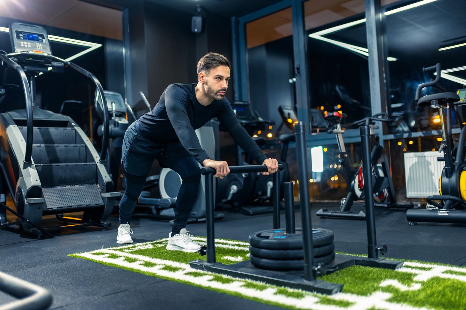 Muscular sporty man pulls weights across the floor of the gym.