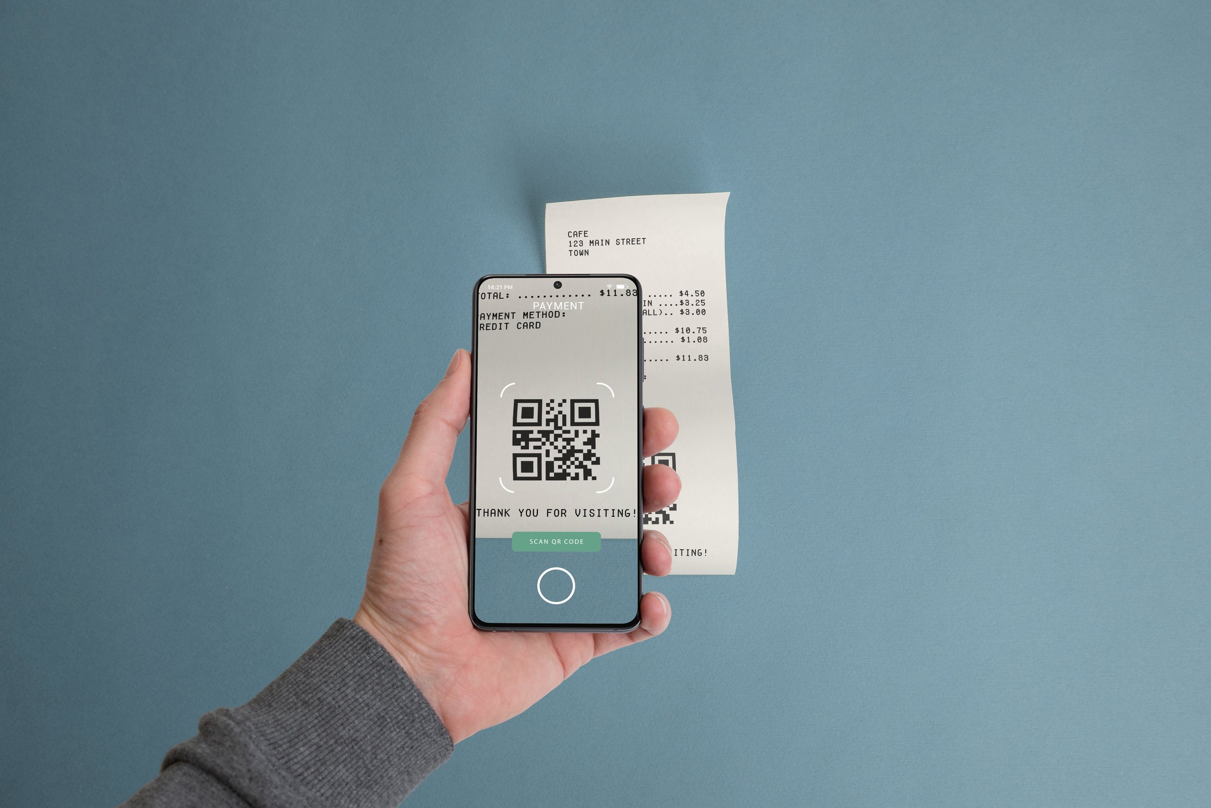 Smartphone scanning a QR code on a paper receipt placed on a table, illustrating the concept of paying bills digitally using mobile technology