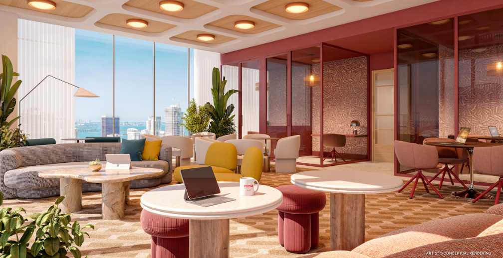 Modern co-working space with colorful furniture, laptops on tables, large windows, and cityscape view.