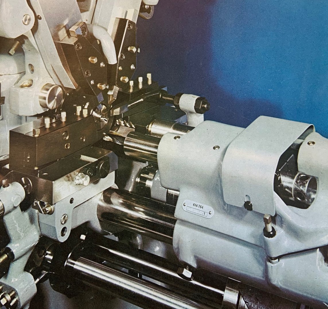 Close-up of an industrial metalworking machine with gears and levers, set against a blue background.