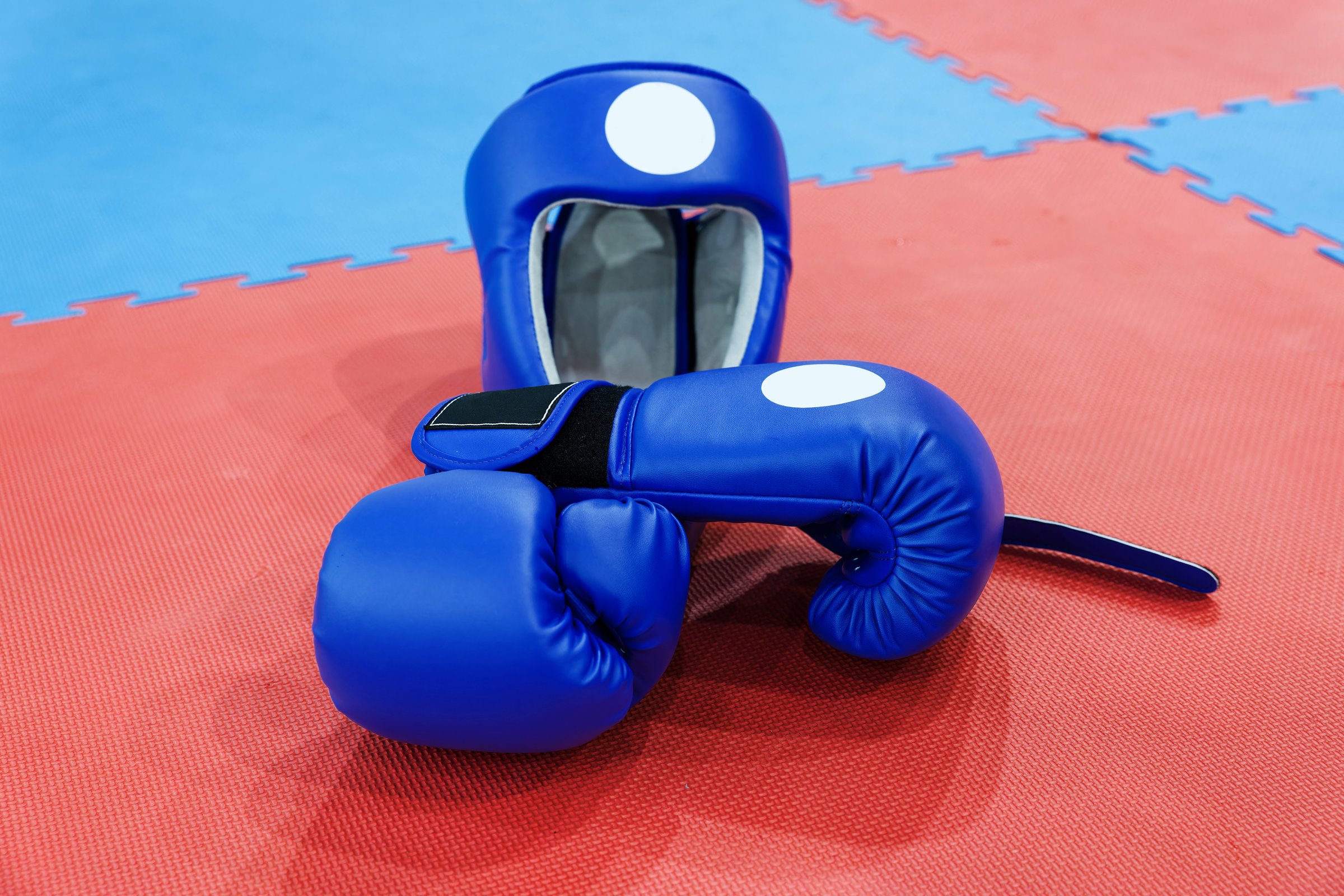 Blue boxing gloves and helmet lies on the ring