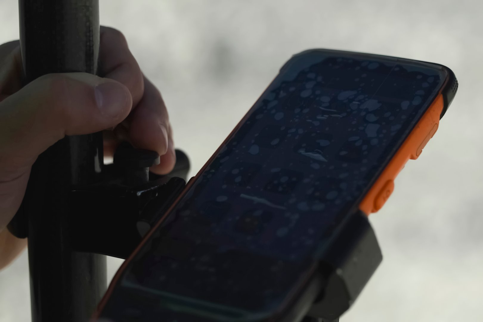 hand holding tripod with shockproof protected smartphone with worn protective film