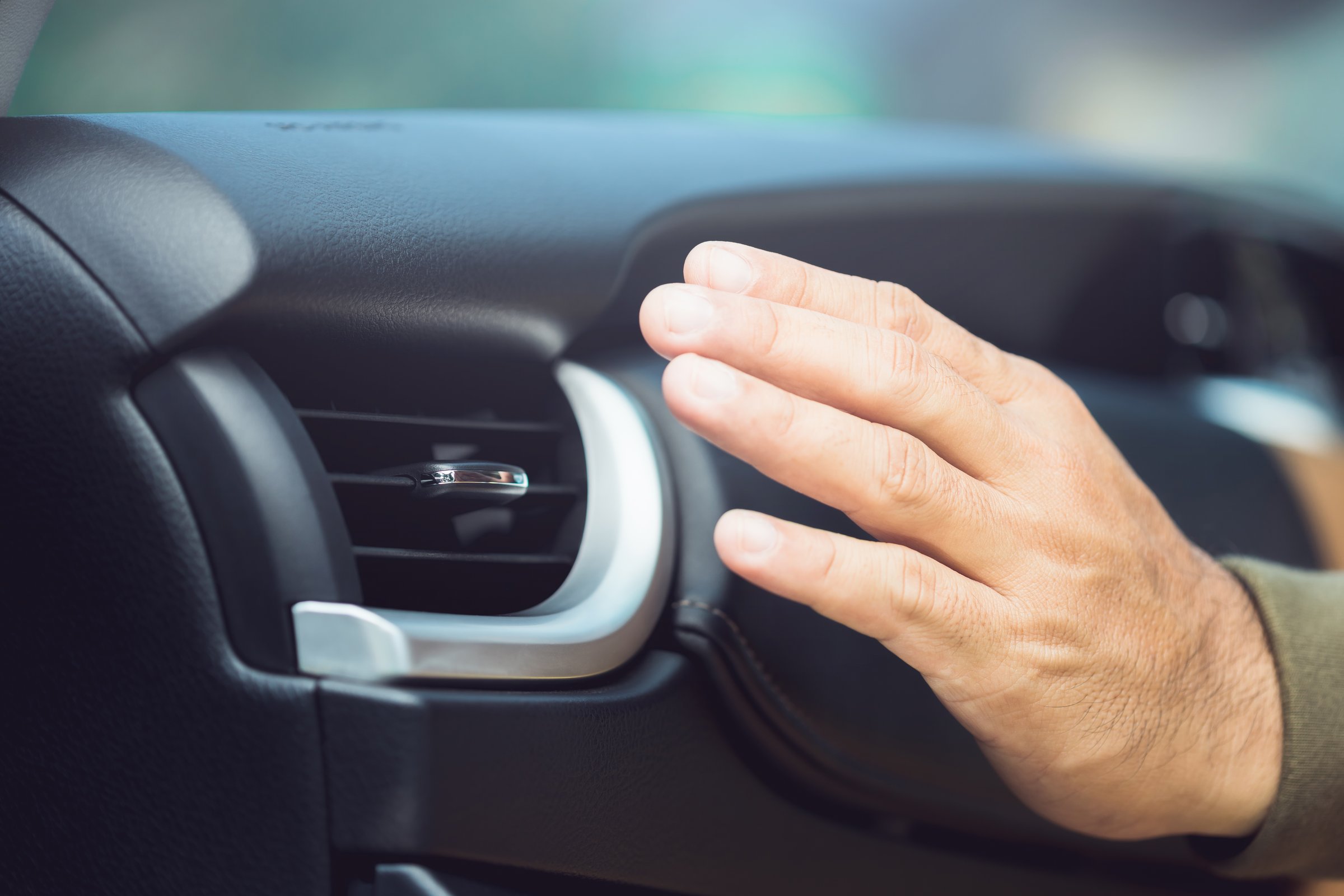 Car owner checks the air conditioning system by feeling the cool air from the vent