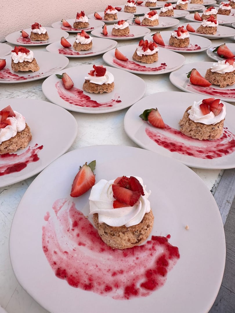 Multiple plates with strawberry shortcakes topped with whipped cream and fresh strawberries in a neat arrangement.