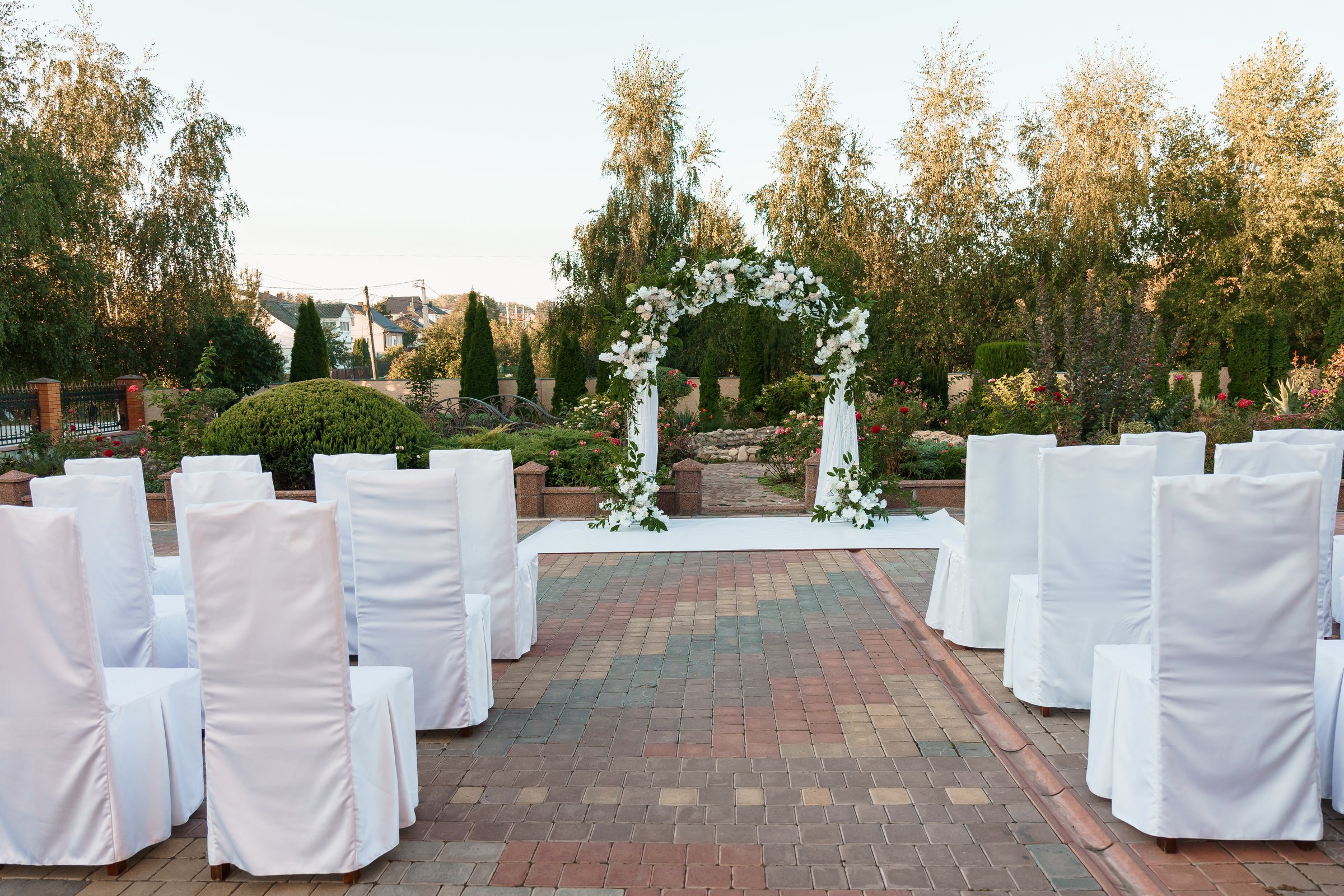 Elegant Outdoor Wedding Setup with Floral Arch and White Chairs.