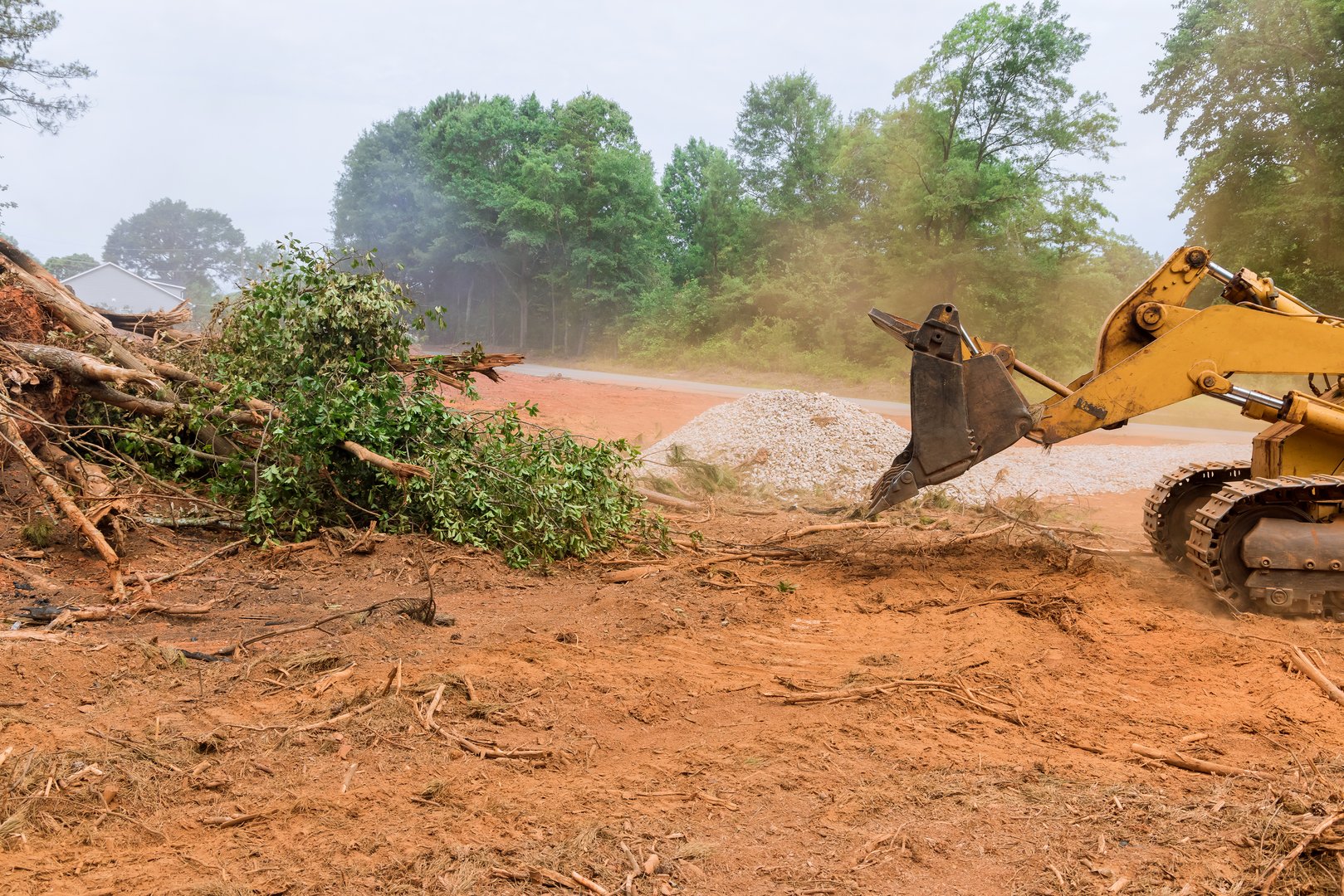 During the uprooting of trees and deforestation, a tractor is working the process to prepare the land for new house construction in subdivision complex
