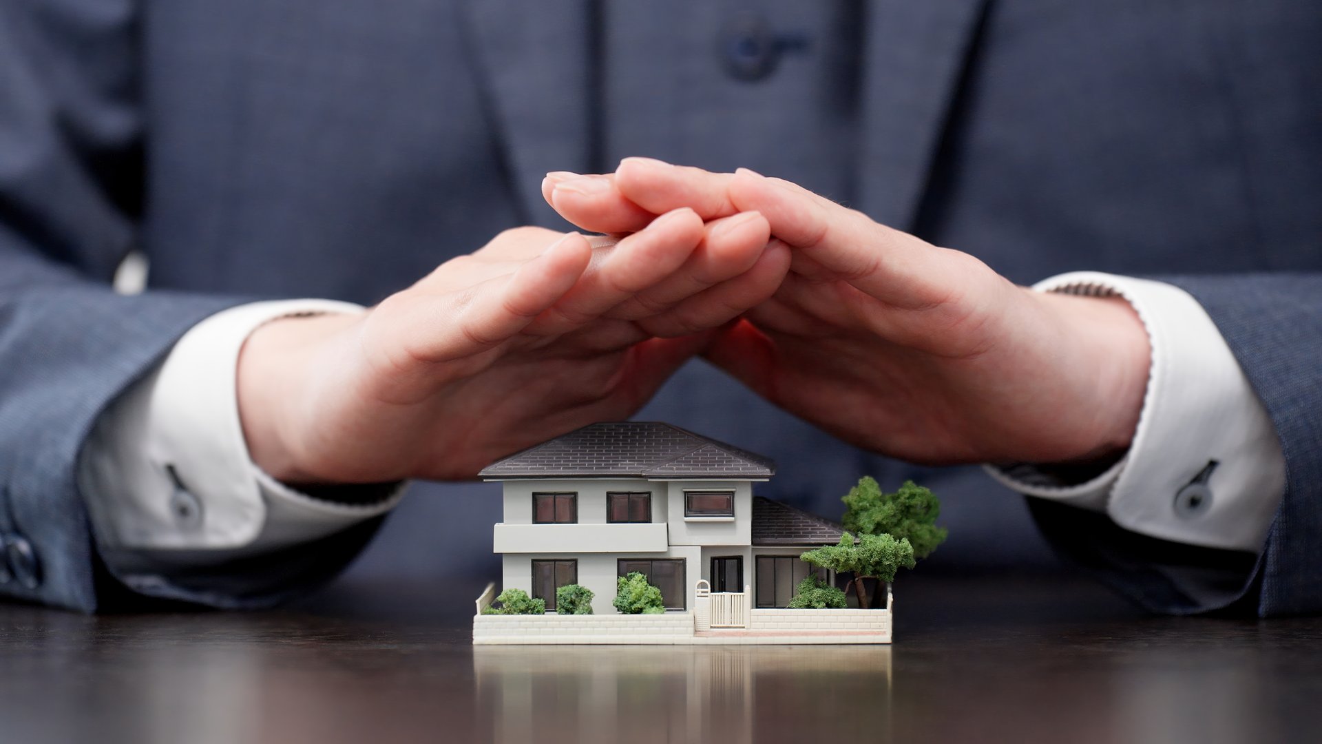 Hands of a businessman protecting his house