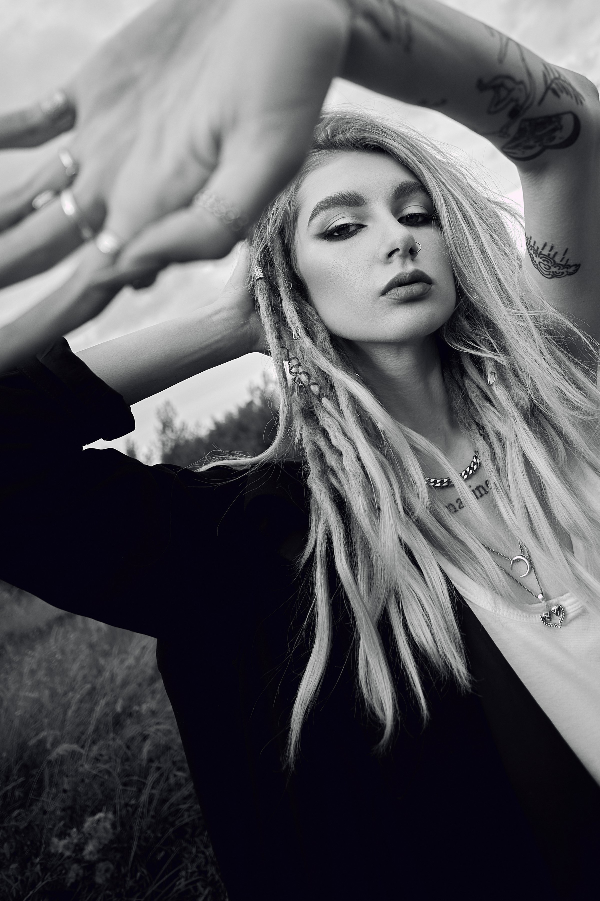 A woman with long blonde dreadlocks poses for a portrait with a serious expression.