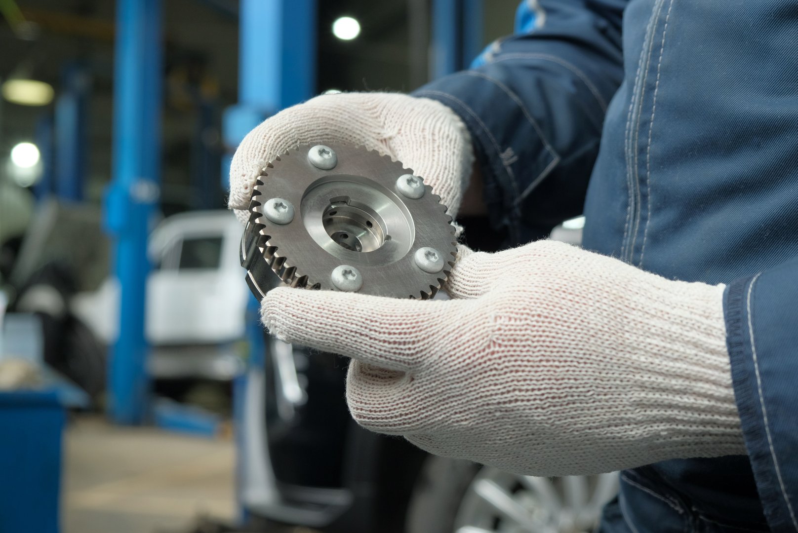 An auto mechanic inspects and monitors the serviceability and integrity of a new gear before replacing it.