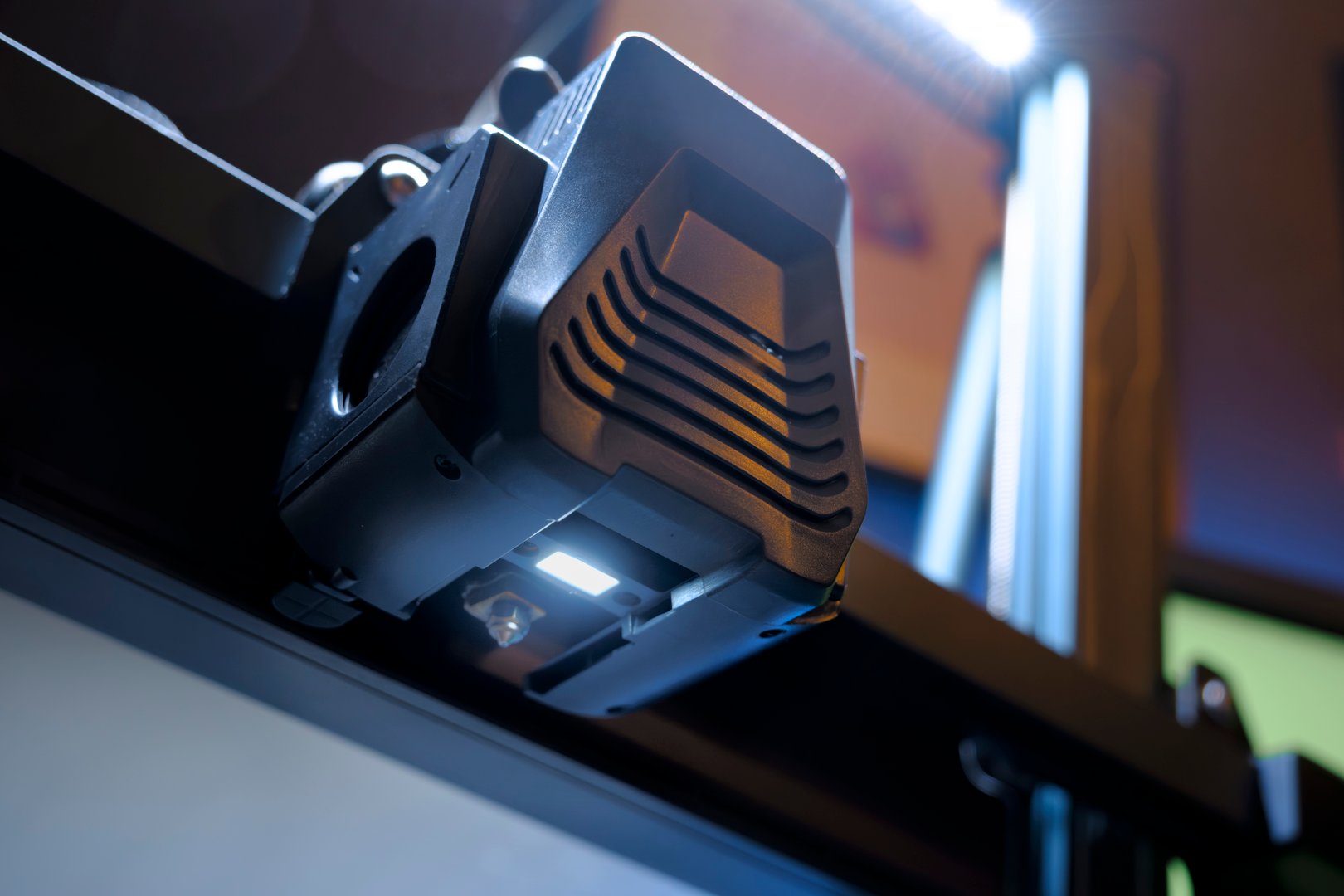 Close-up View of a 3D Printer's Nozzle Showcasing the Intricate Details of Its Design. The Lighting Emphasizes the Technological Advancement in Home Fabrication.