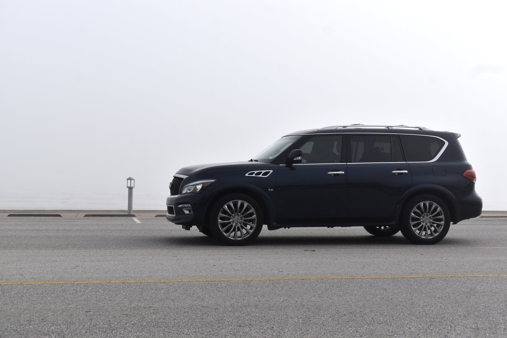Galveston Beach, Texas USA December 21, 2025- A portrait of a black Infiniti Qx80 during an exceptionally foggy day, where heavy coastal mist transforms the shoreline into a dramatic, atmospheric backdrop.