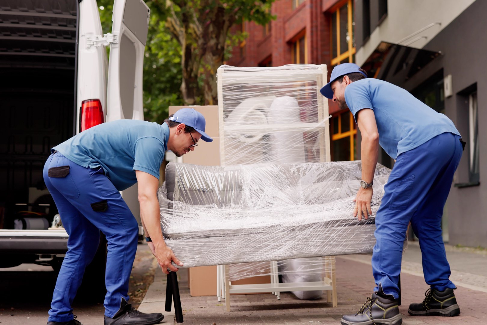 Professional Movers Outside Delivering Furniture Removal Service With Truck And Van.