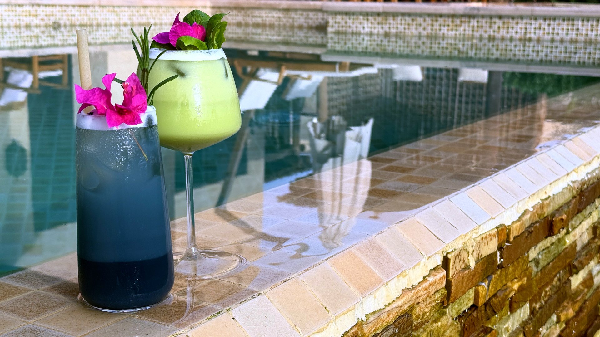 Bartender mixing vibrant blue and green cocktails adorned with fresh flowers