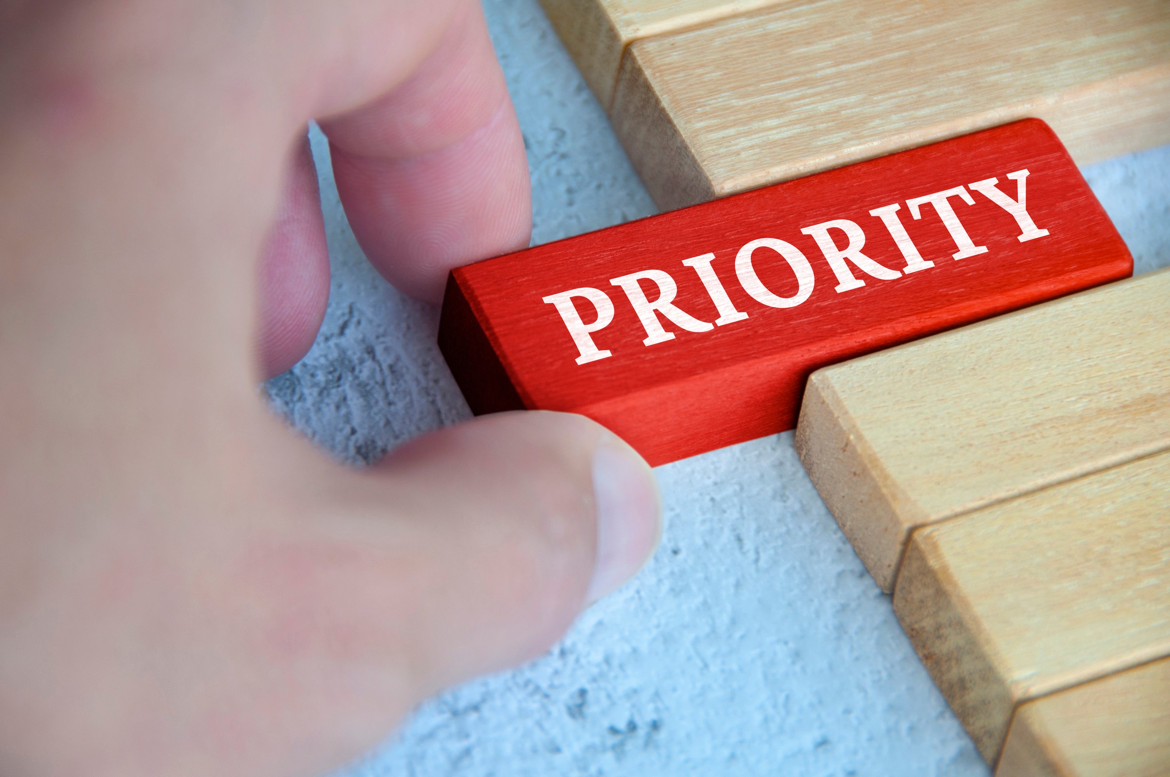 Hand placing red wooden blocks with text - Priority. Priority and business concept.
