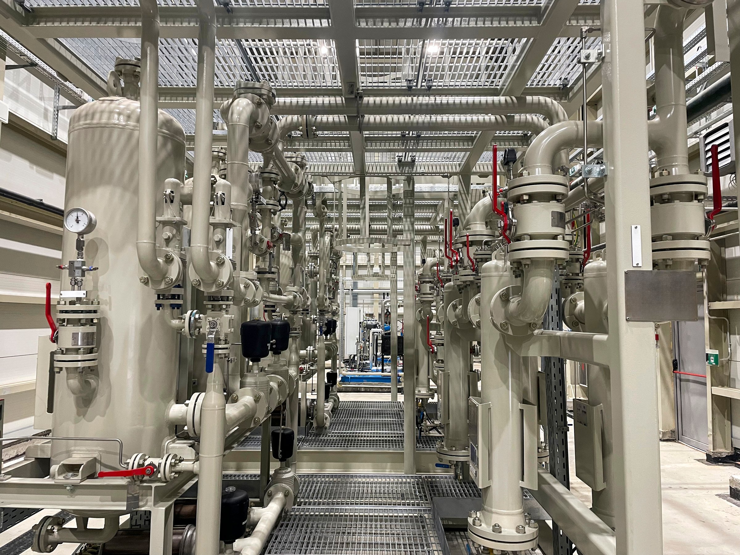 Interior view of a modern industrial facility showcasing a complex network of pipes, valves, and gauges used for fluid or gas processing in a manufacturing or energy plant.