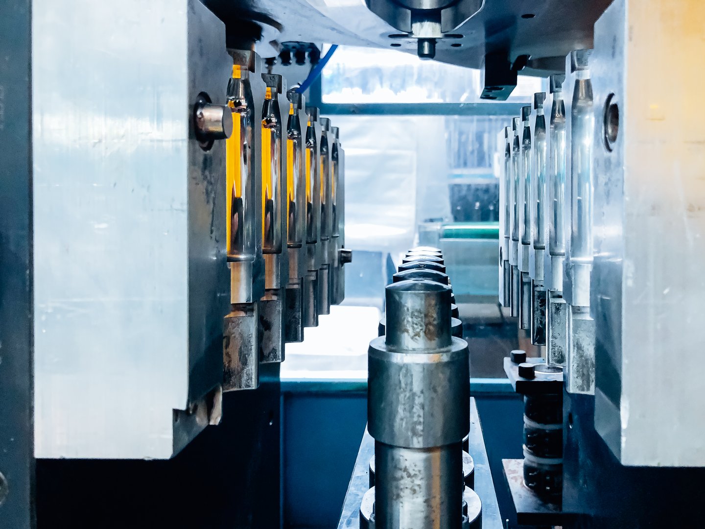 Blow molding machine producing clear plastic bottles on factory production line.