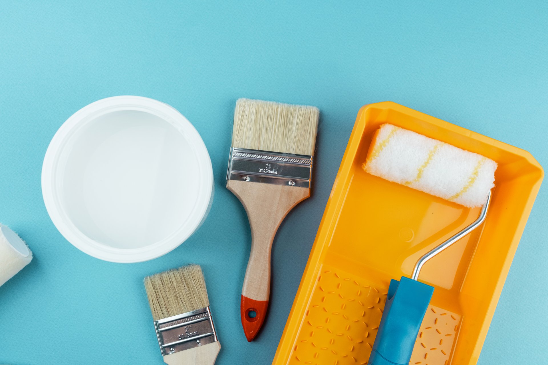 Painting tools layout on blue background with bucket and tray for DIY home renovation and workspace concept