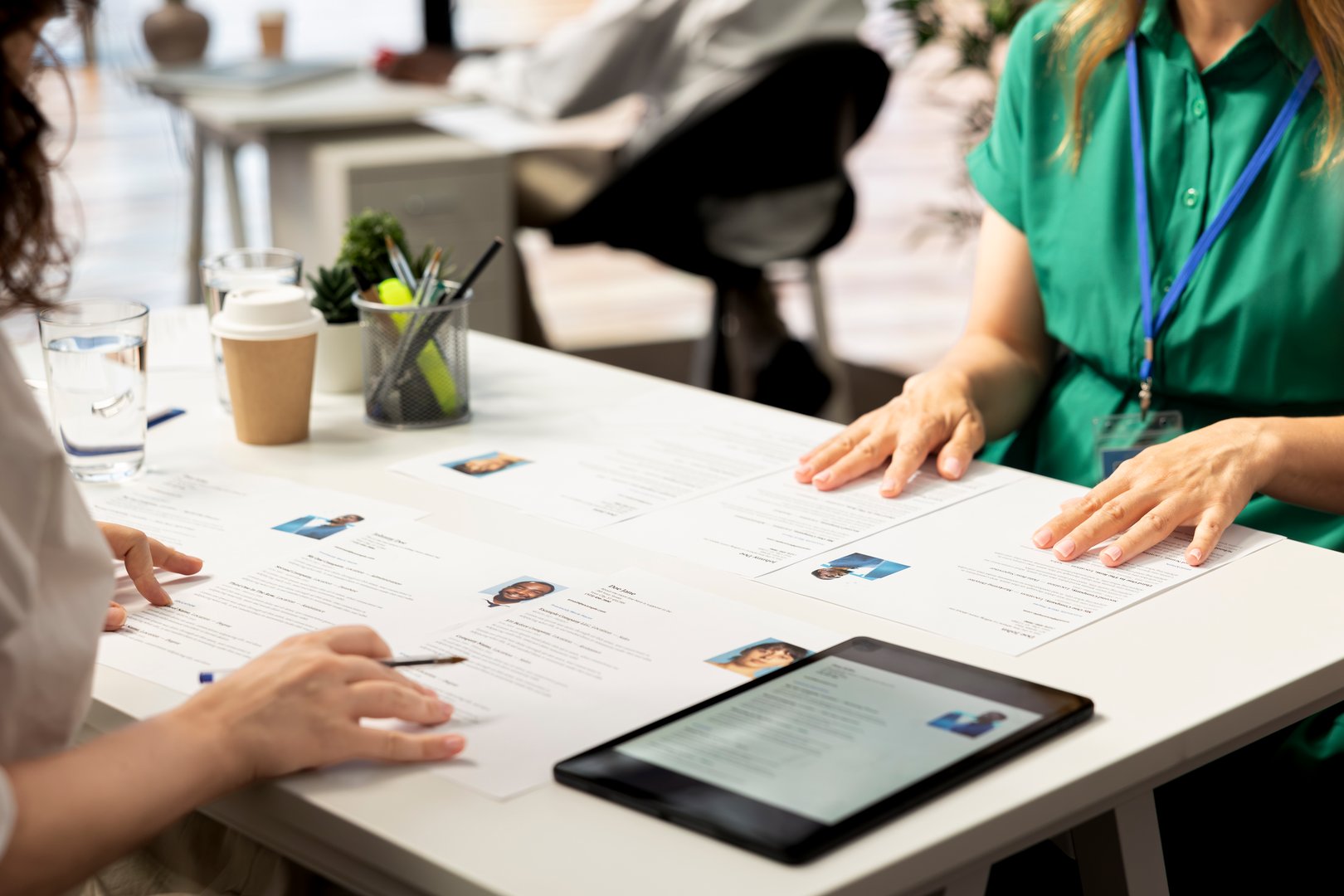 HR staff members using tablet to look at CVs and do background checks to potential job applicants. Headhunters use device to read resumes, attracting qualified candidates for vacant startup position