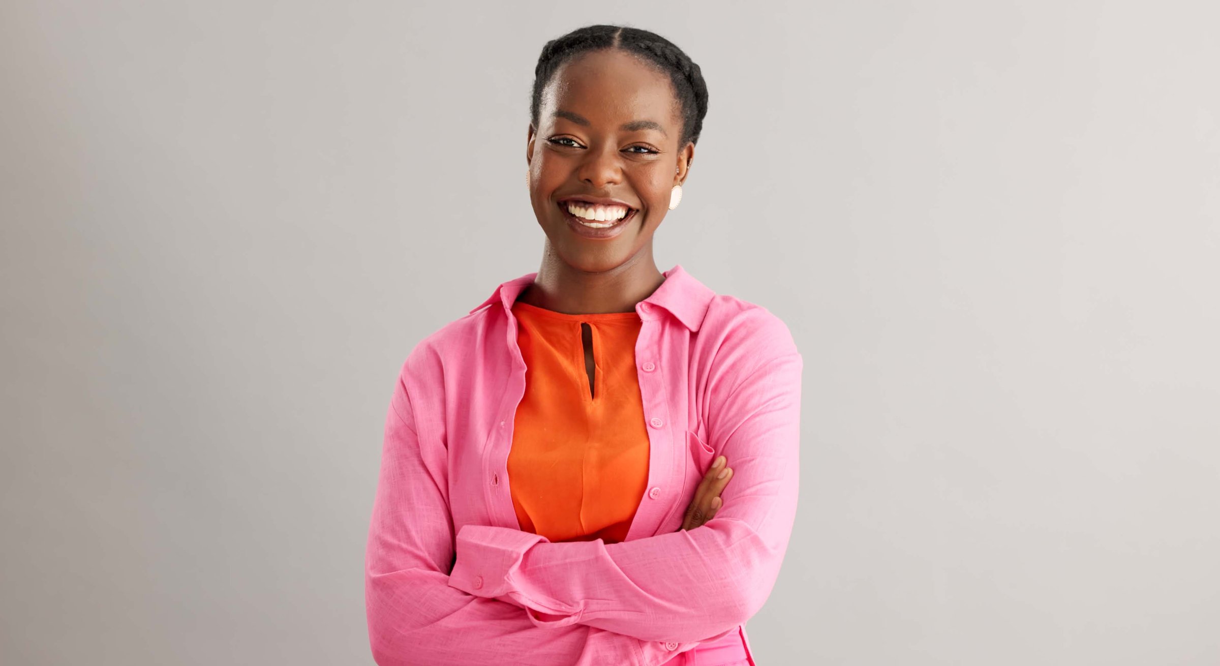 Black woman, arms crossed and portrait with smile in studio for fashion, confidence and pride on grey background. African person, happy and face of person with trendy, style and positive mindset