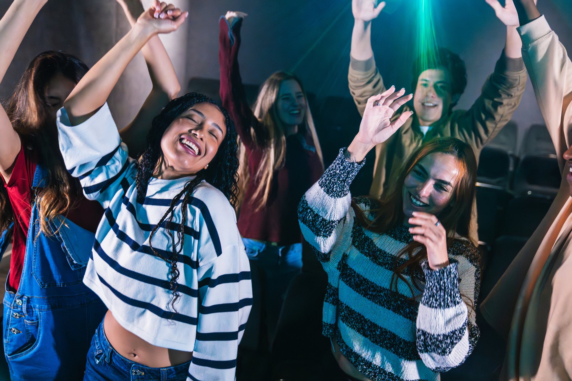 Group of friends dancing joyfully and enjoying live music together at a vibrant concert hall, surrounded by excitement and energy