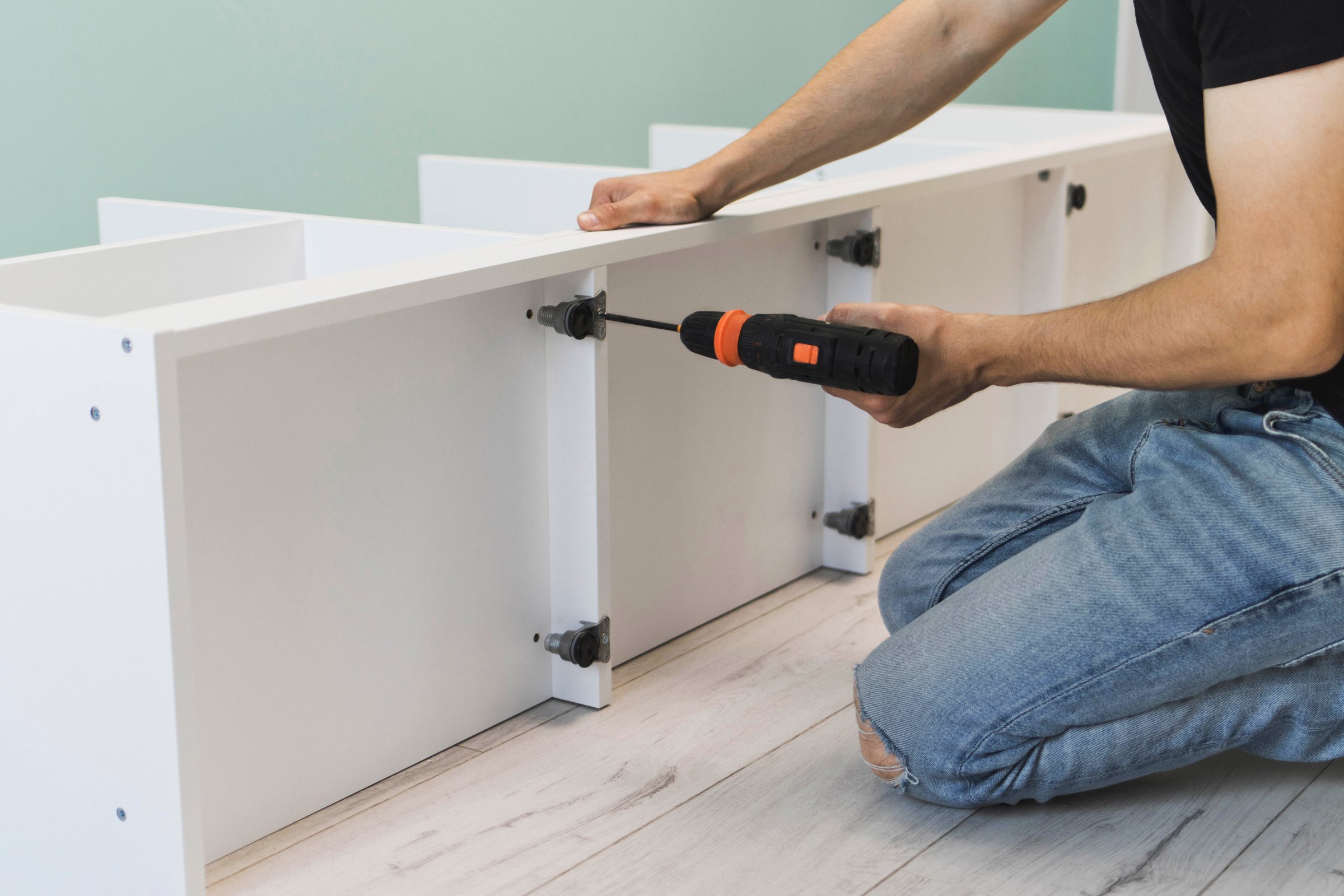A young craftsman assembles furniture fittings. Screwing the confirmat close-up. Professional furniture assembling. Installation of new furniture. Furniture assembly.