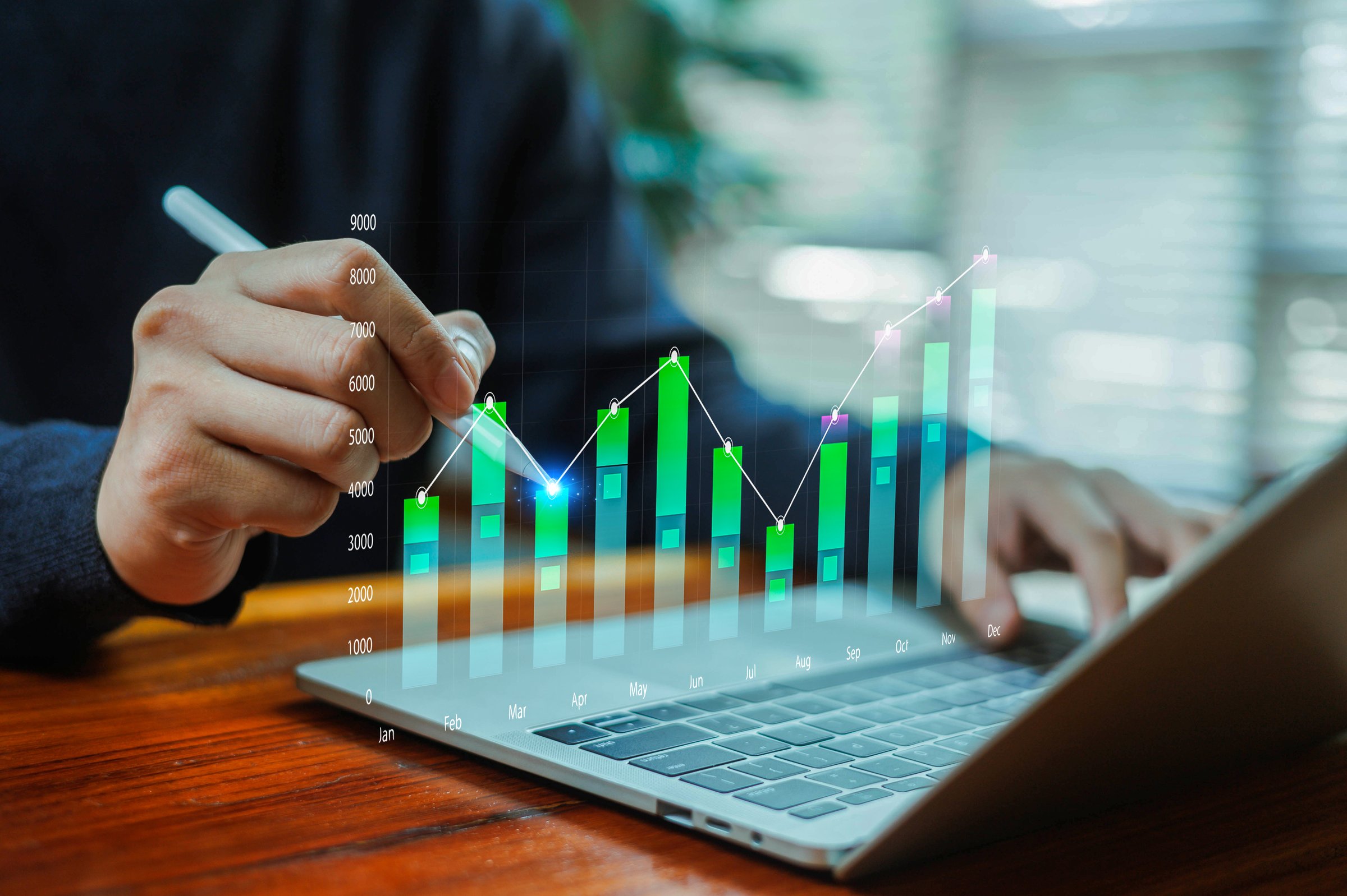 A person analyzing a digital bar and line chart on a laptop, highlighting monthly growth, financial performance, data analytics, and business strategy for investment and economic planning concepts.