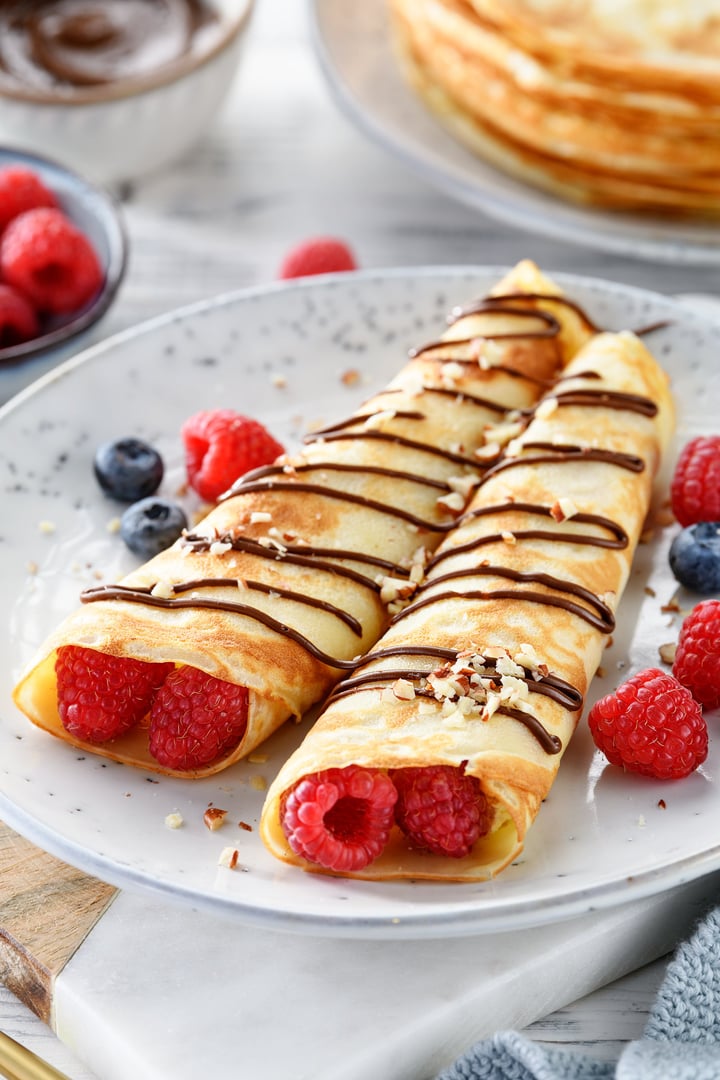 Crepes or thin pancakes with cottage cheese filling, fresh berries and chocolate sauce , sprinkled with nuts
