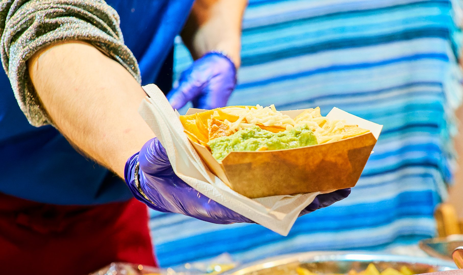 Faceless cutout of a cook with gloves cooking nachos at a food truck.