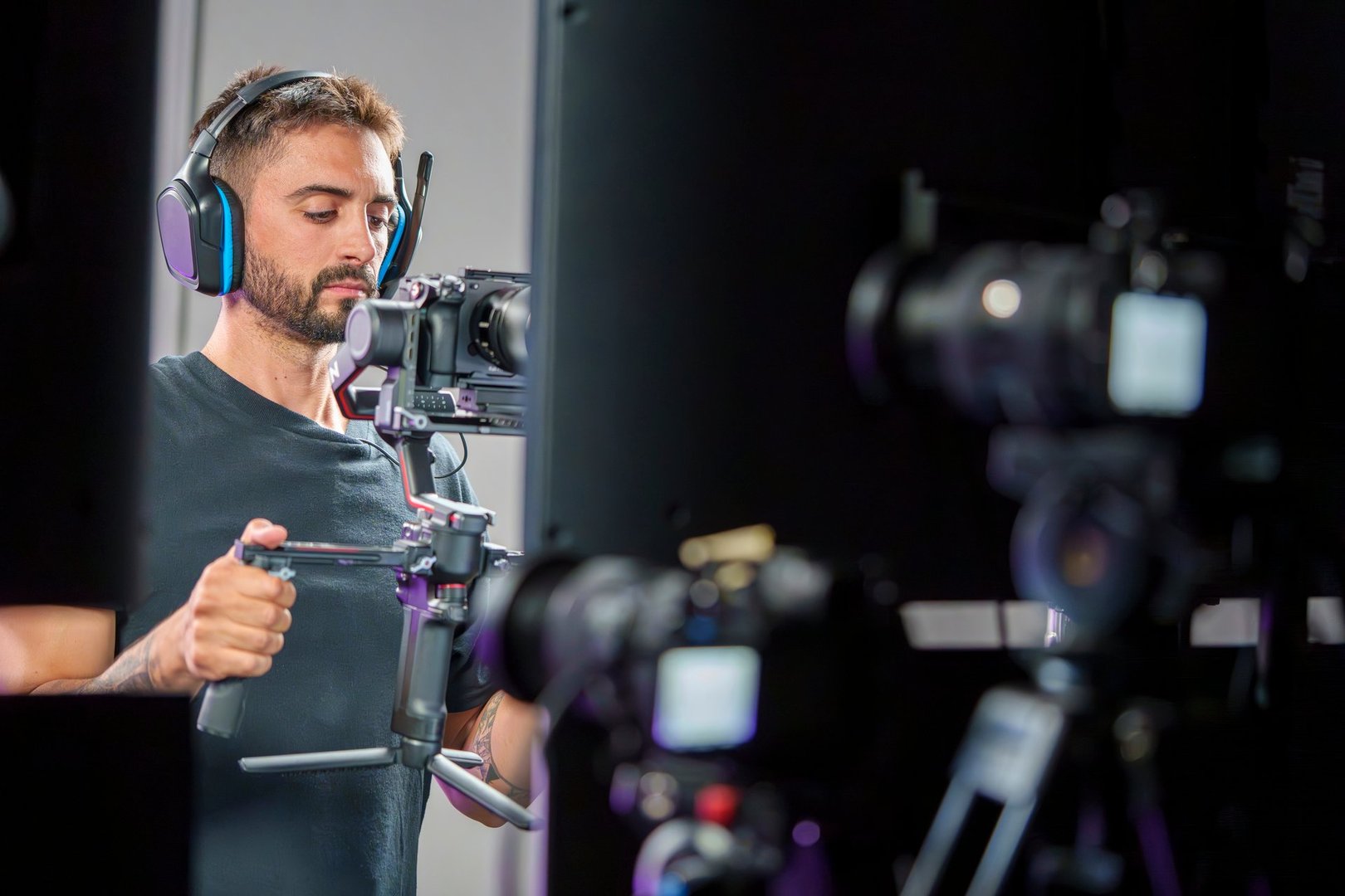 Young Male Camera Operator Using a Gimbal for Filming on a Professional TV Set with Headphones