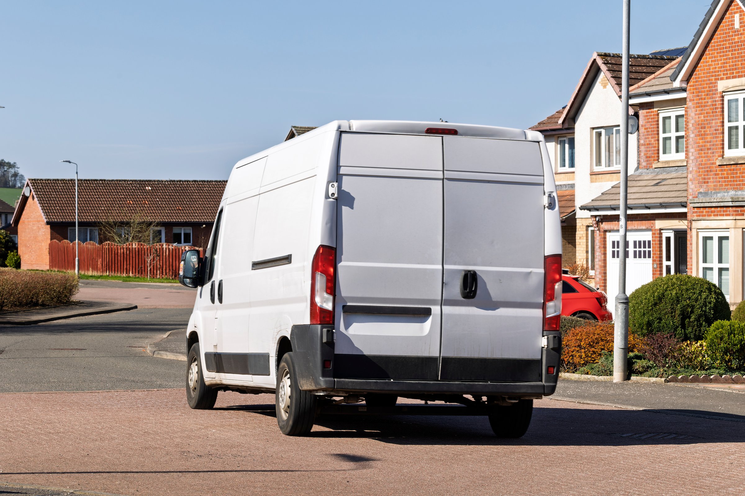 Rear view of an unbranded white van on a residential street