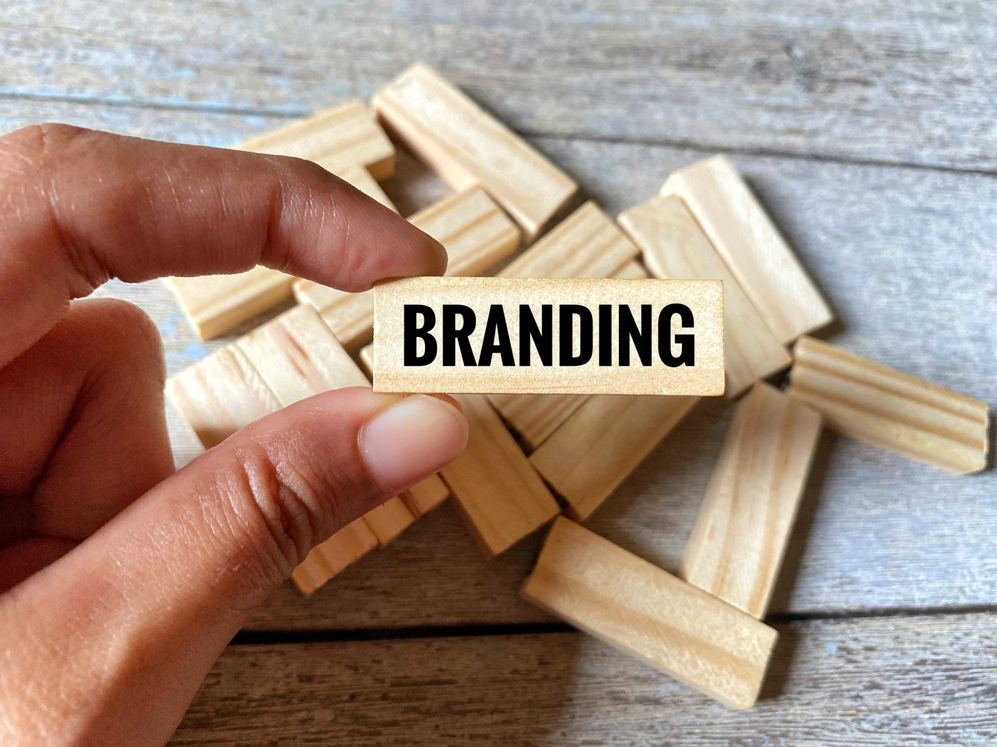 Hand holding a wooden block with written word Branding.