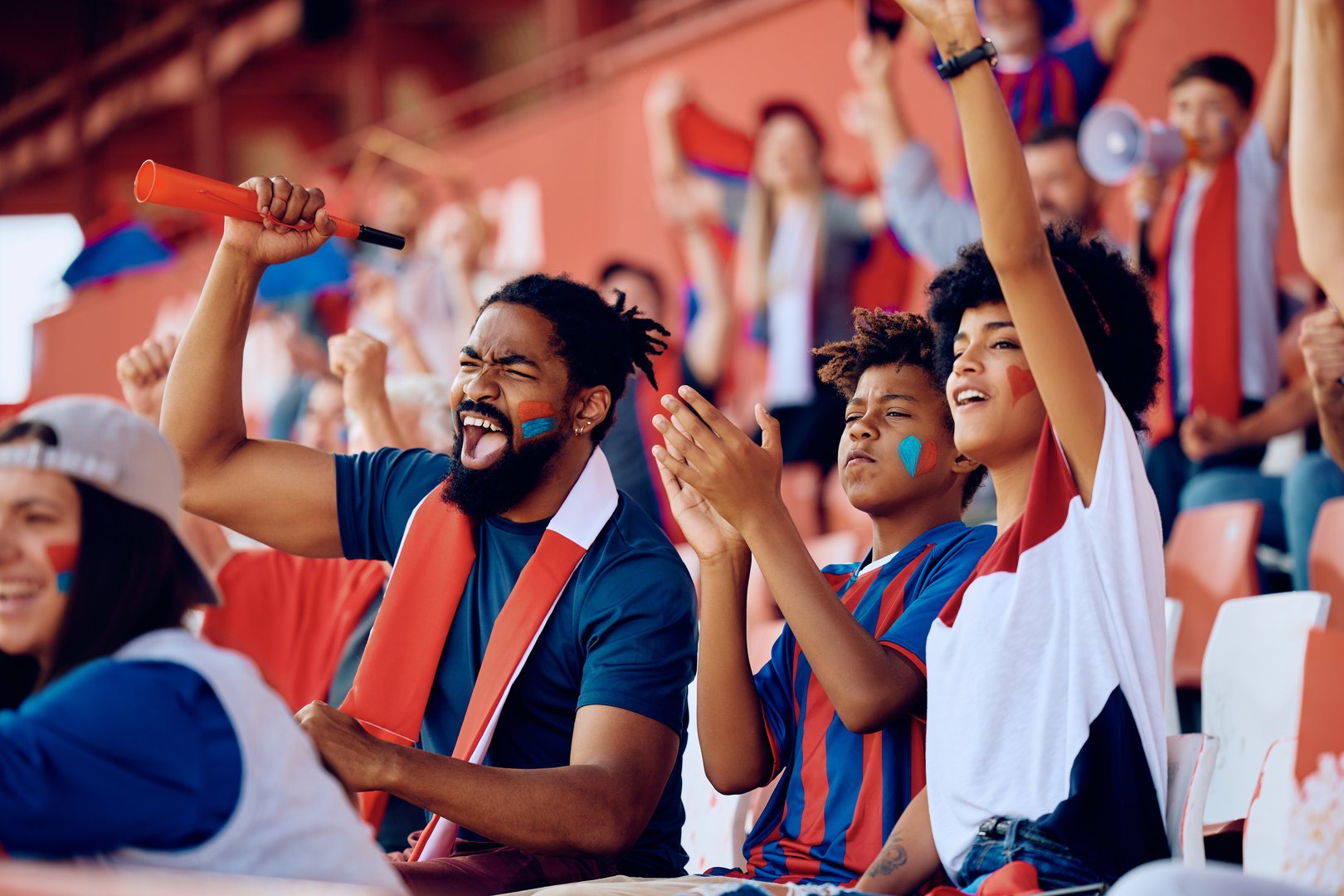 Cheerful African American family celebrating the victory of their favorite team during sports game at the stadium.