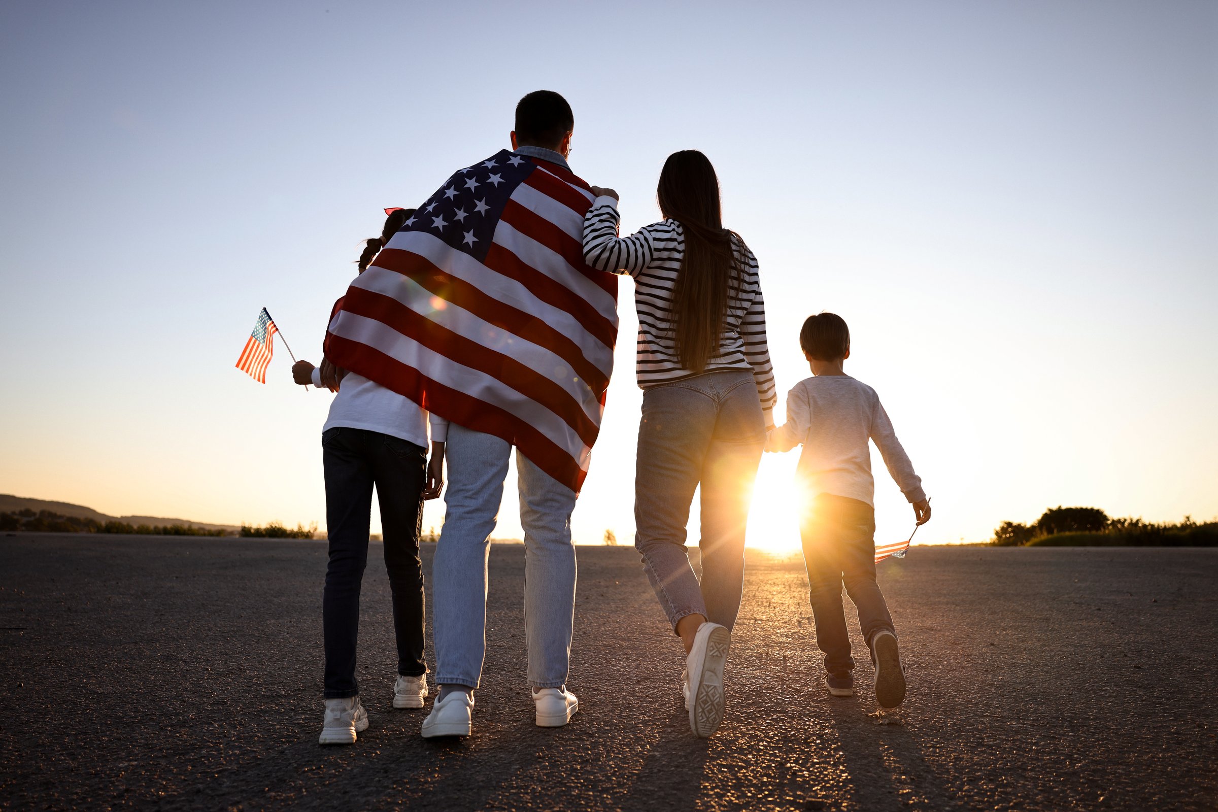 Family with flags of USA outdoors, back view
