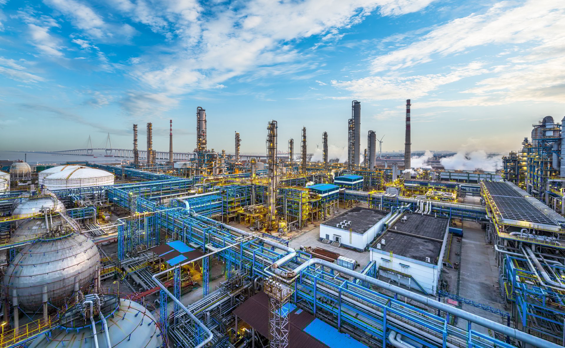 Aerial view of a large oil refinery and chemical plant under a vast sky, illustrating the scale and complexity of the petrochemical industry.