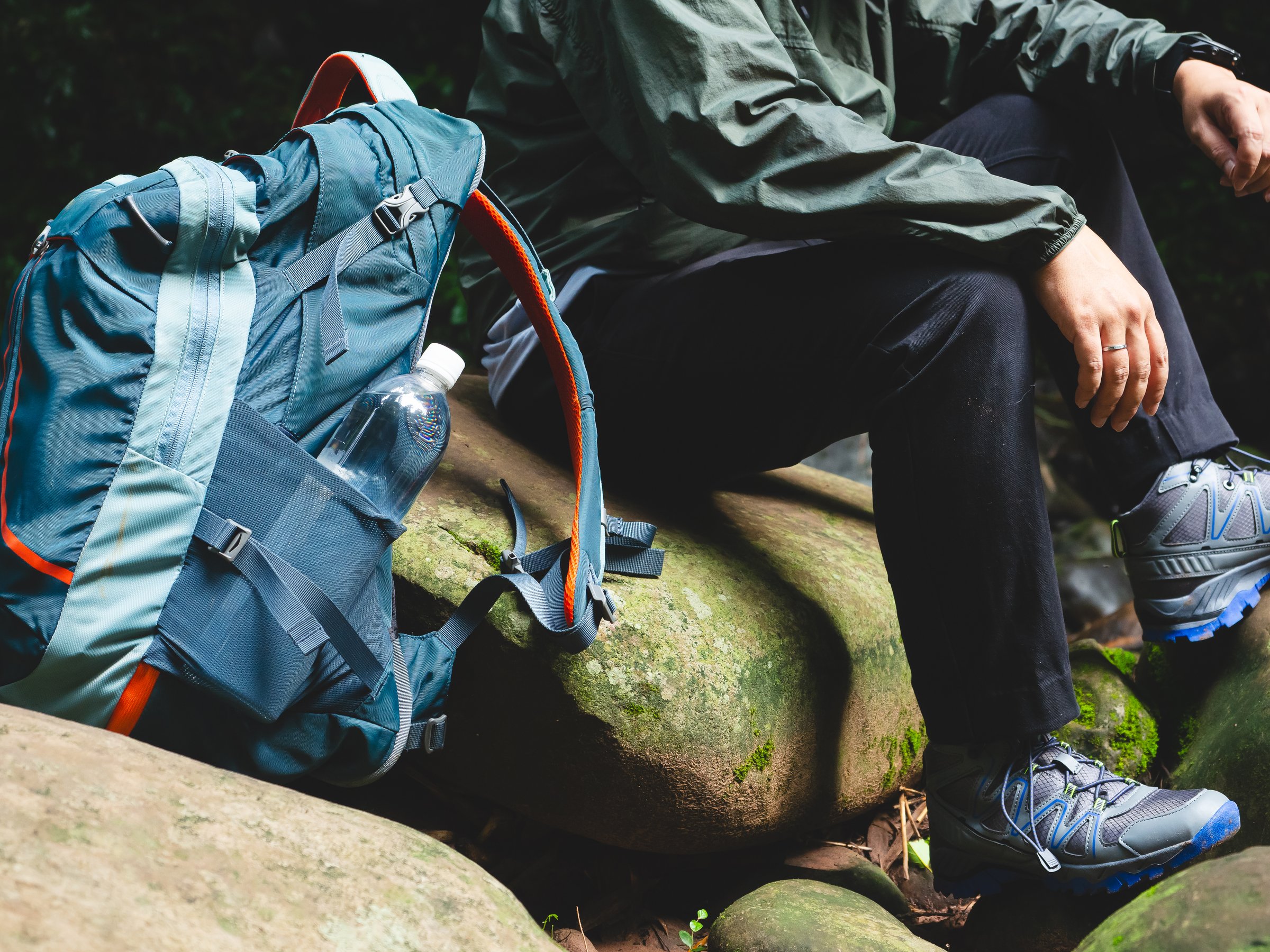 Close-up of backpack and man resting with water bottle during hiking